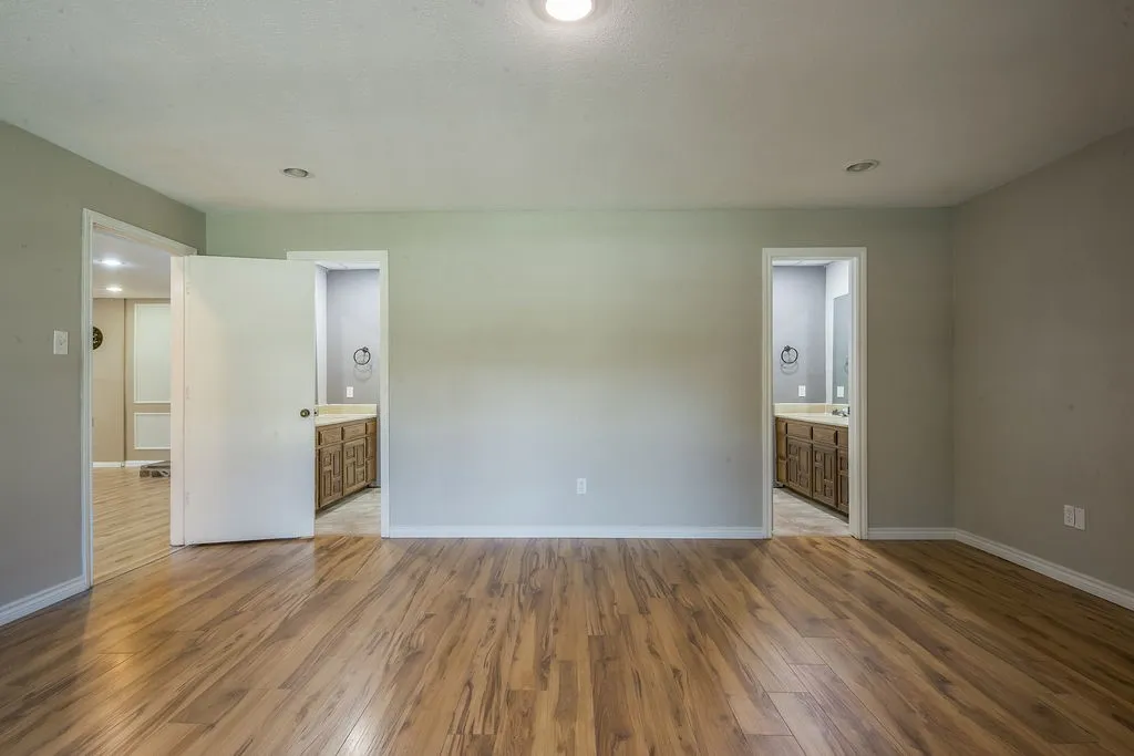 Spacious room featuring wood-finish flooring, light neutral wall tones, and recessed ceiling lighting