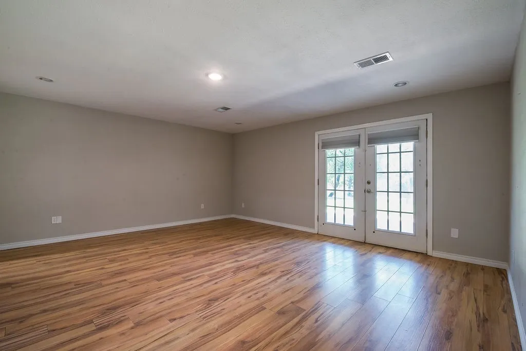 Spacious room featuring, recessed lighting, French doors with privacy blinds.