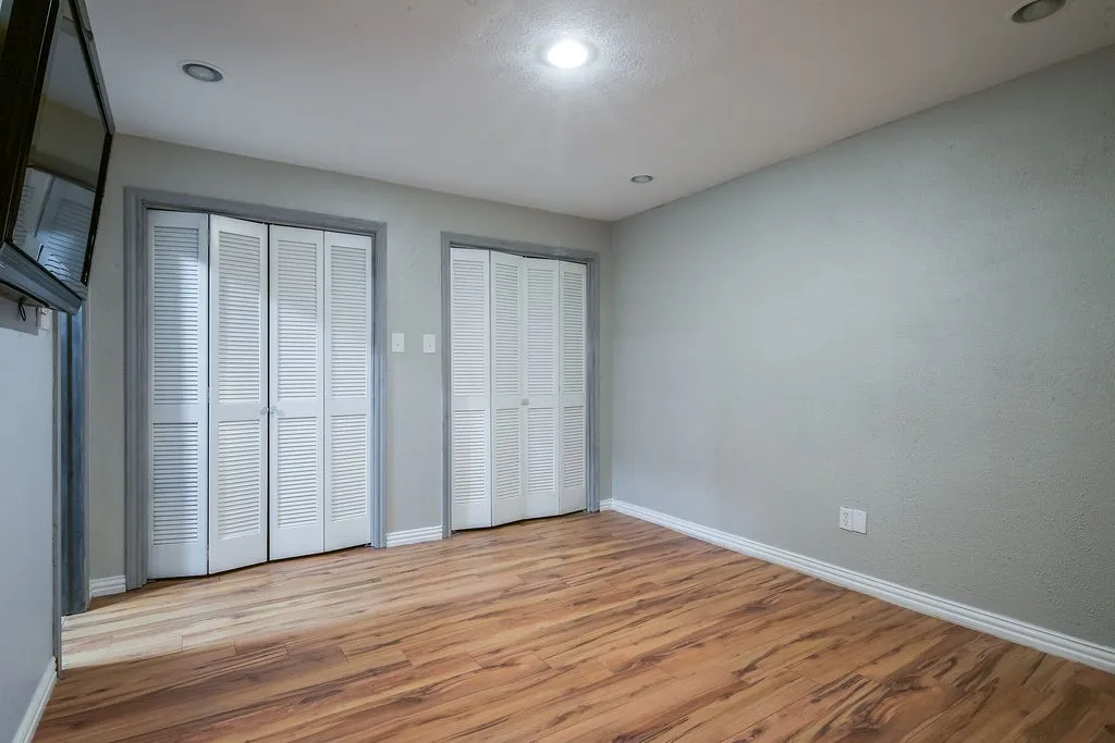 Room featuring wood-finish flooring, recessed lighting, and two sets of louvered bifold doors