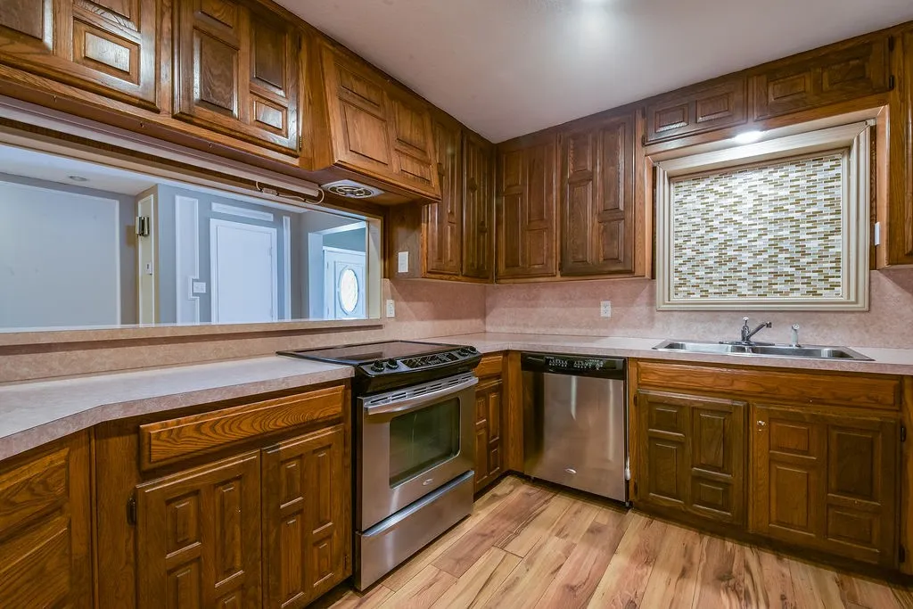 Kitchen featuring wood-finish flooring, oak cabinetry, stainless steel appliances, and solid surface countertops.