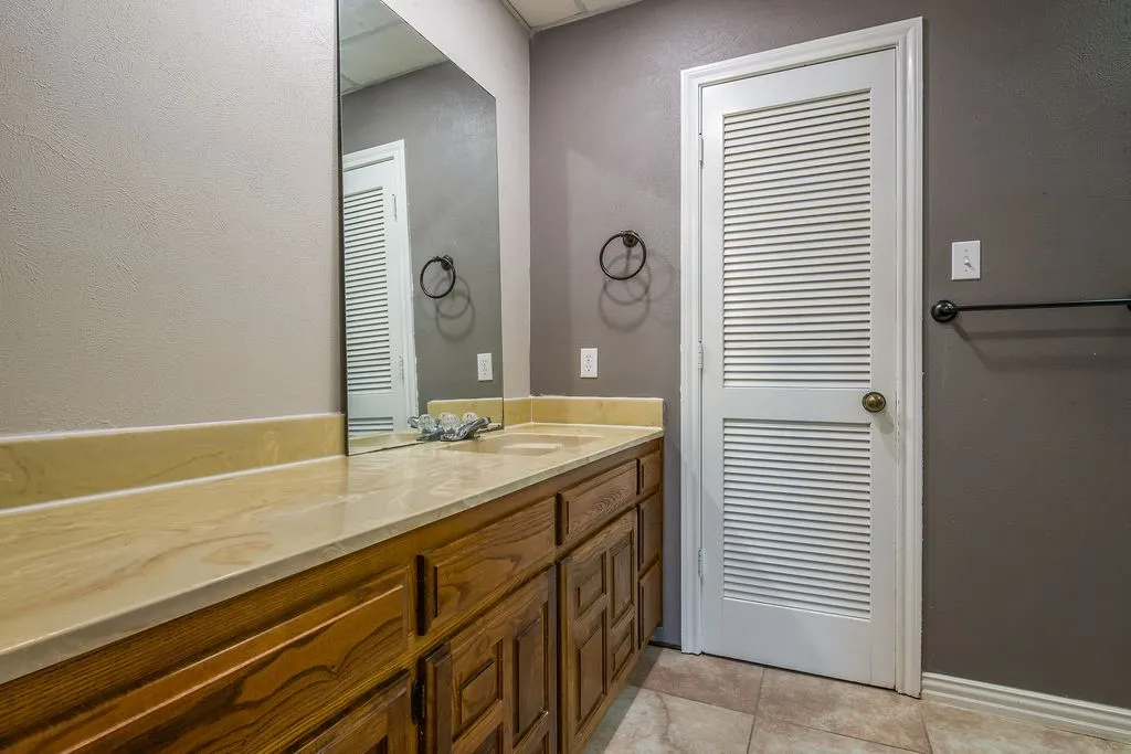 Bathroom vanity featuring a light-toned countertop, dual integrated sinks, and wood cabinetry