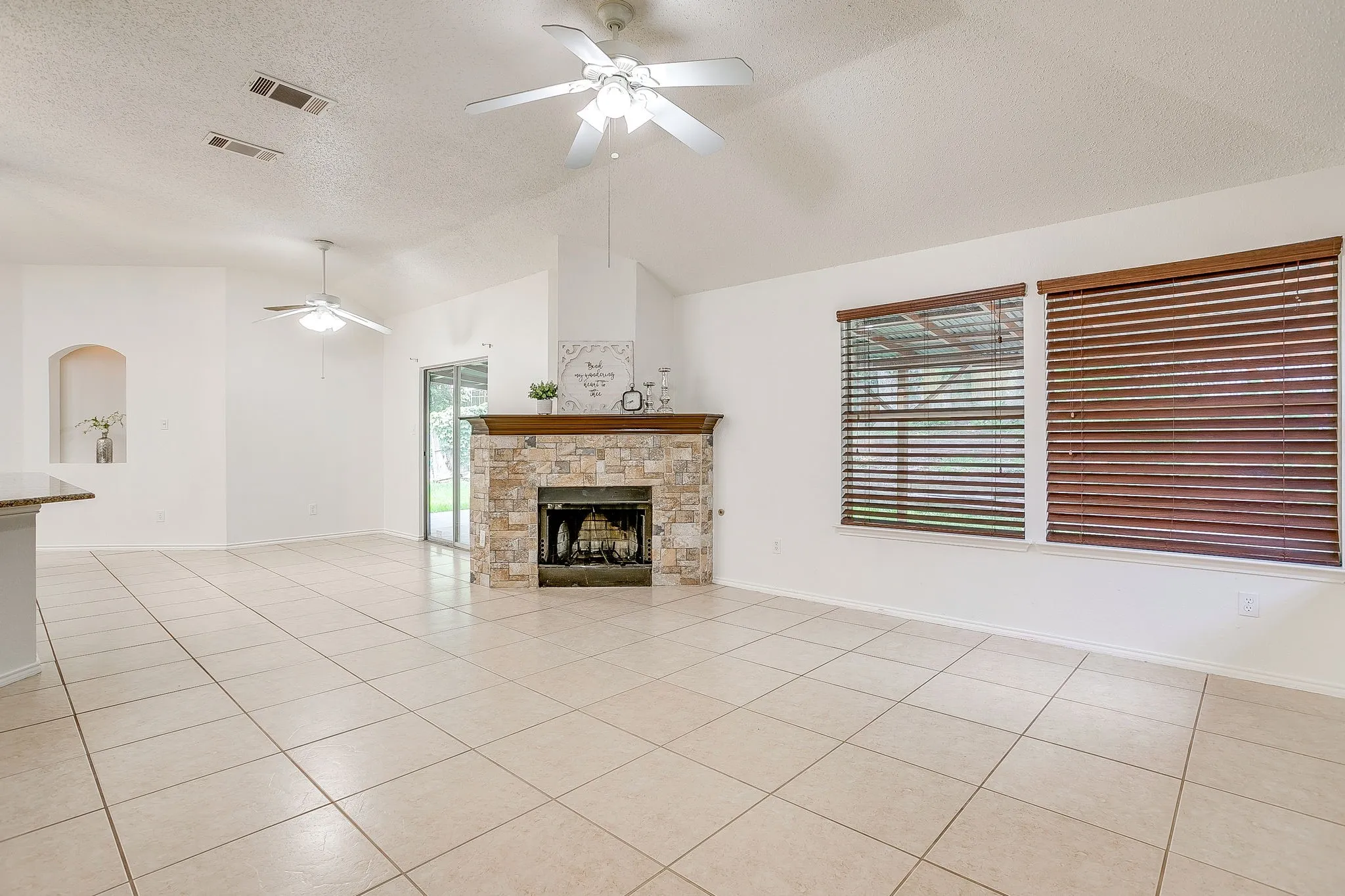 Living room featuring a prominent corner stone fireplace with wood mantel.
