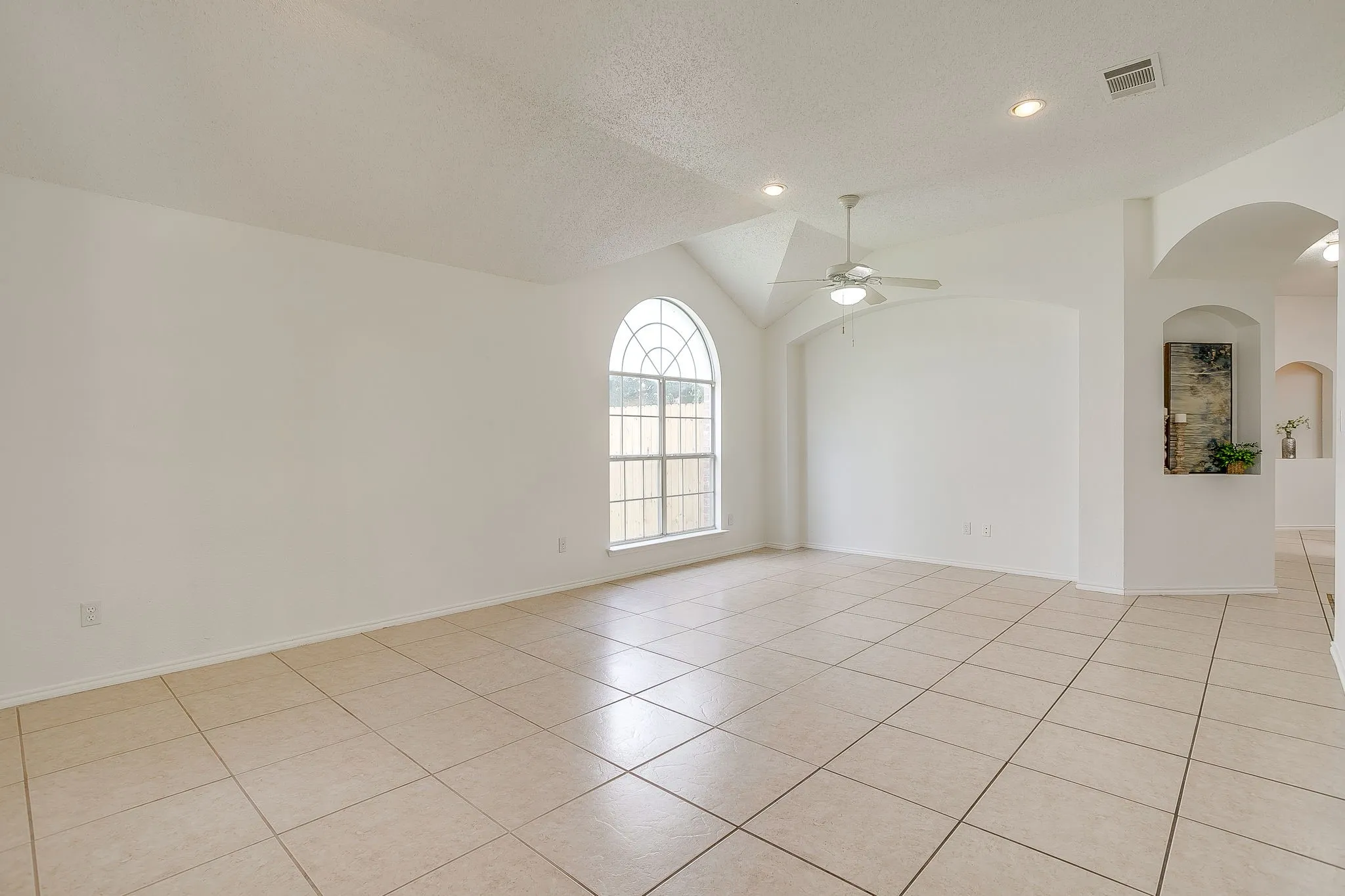 The living room features an arched window and light toned tile.