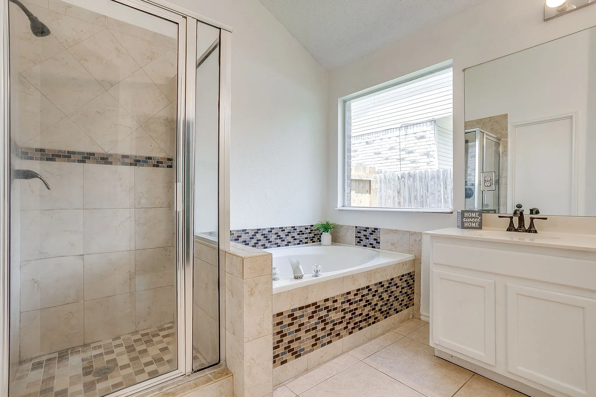 Primary bathroom with separate tub and shower featuring mosaic tile.