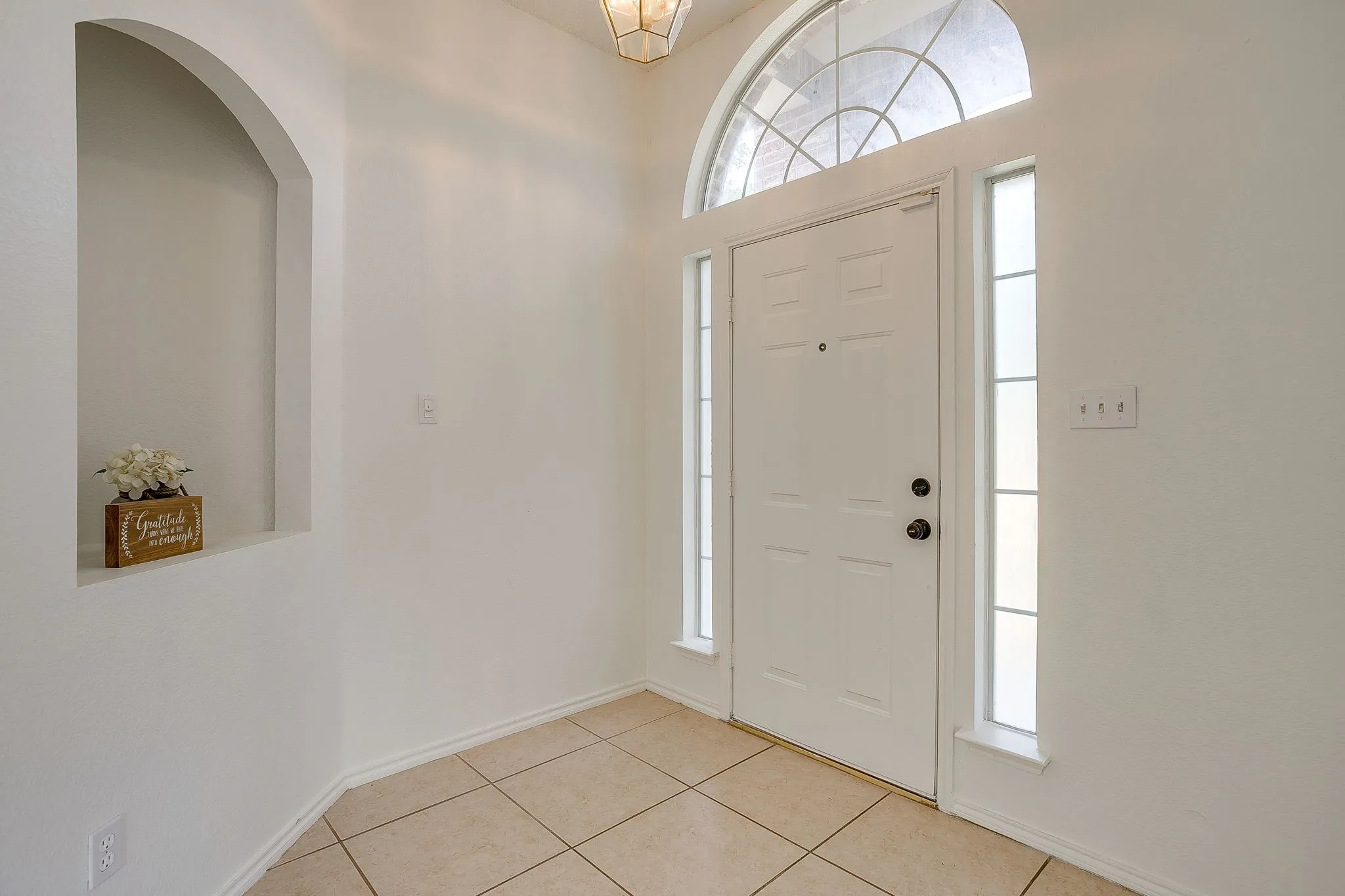 The interior entryway featuring an arched transom window drawing natural light into the foyer.