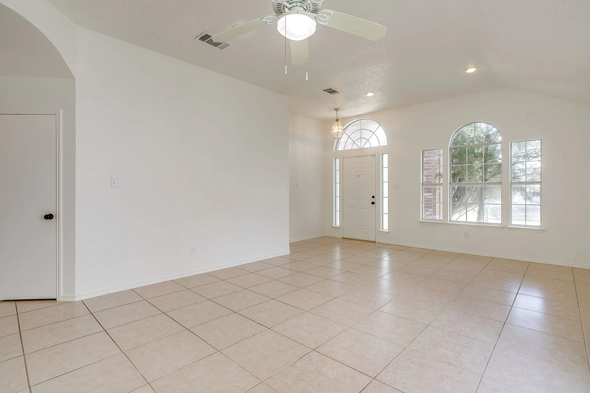 The entryway flowing into the great room featuring multiple windows with arched tops.