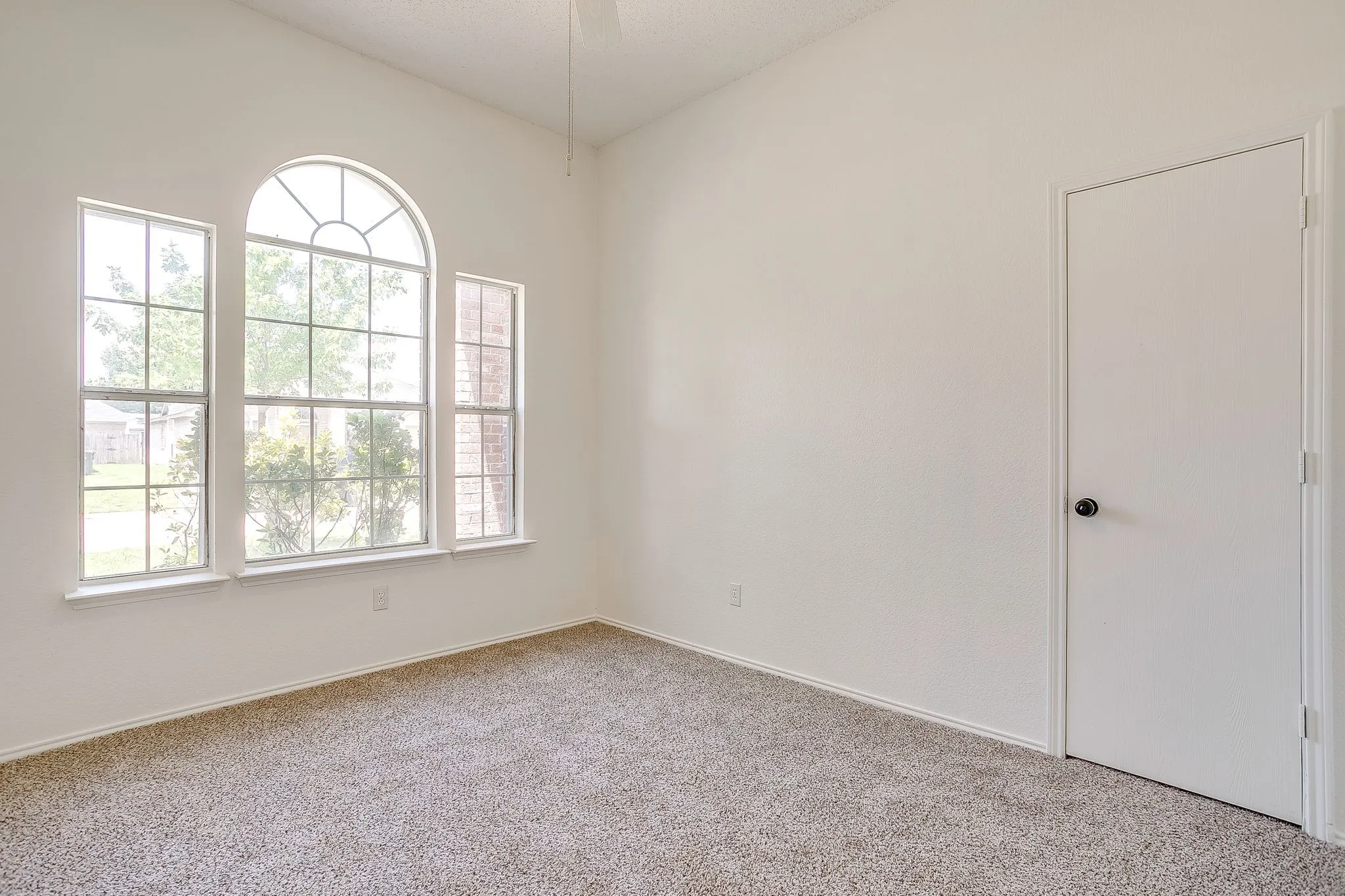 Secondary bedroom featuring large windows with center arched transom window.