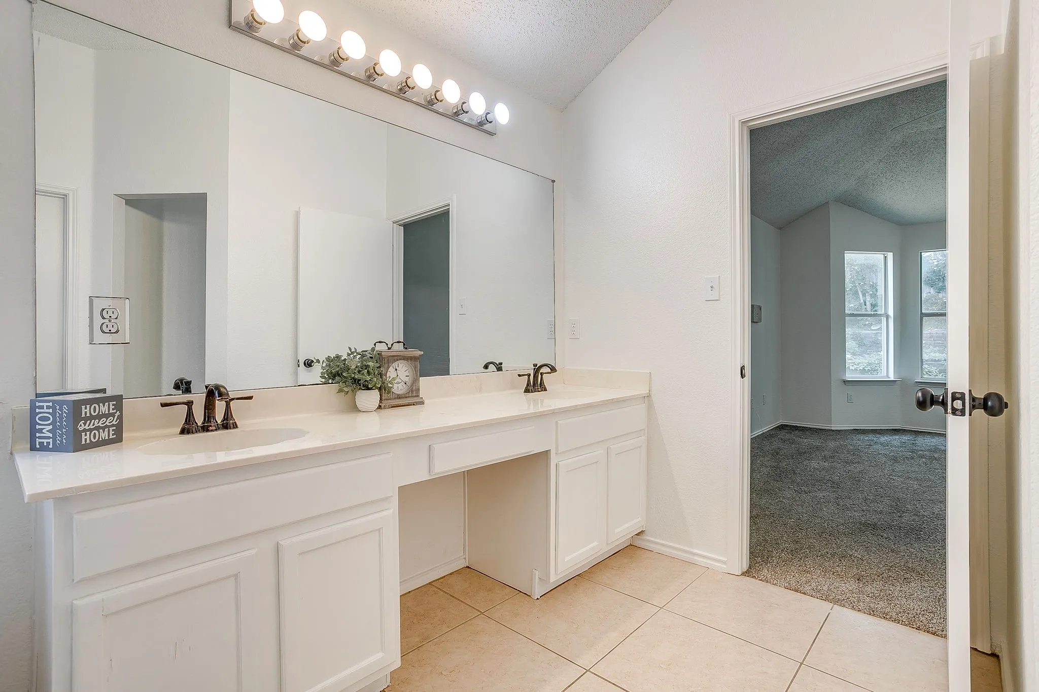 Primary bathroom featuring double vanity and expansive mirror with lighting.
