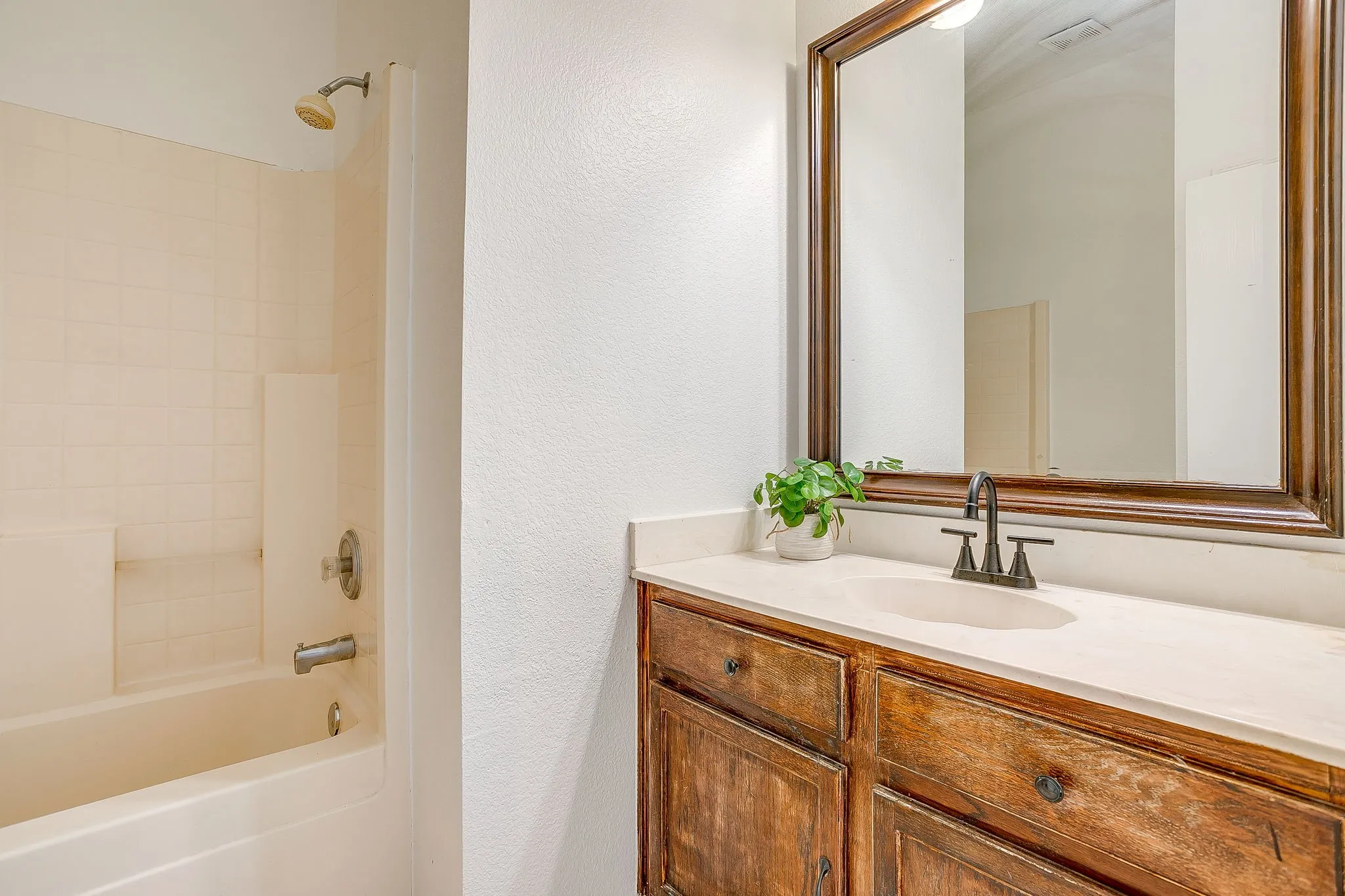Secondary bathroom featuring medium toned cabinets and a tub/shower combination.