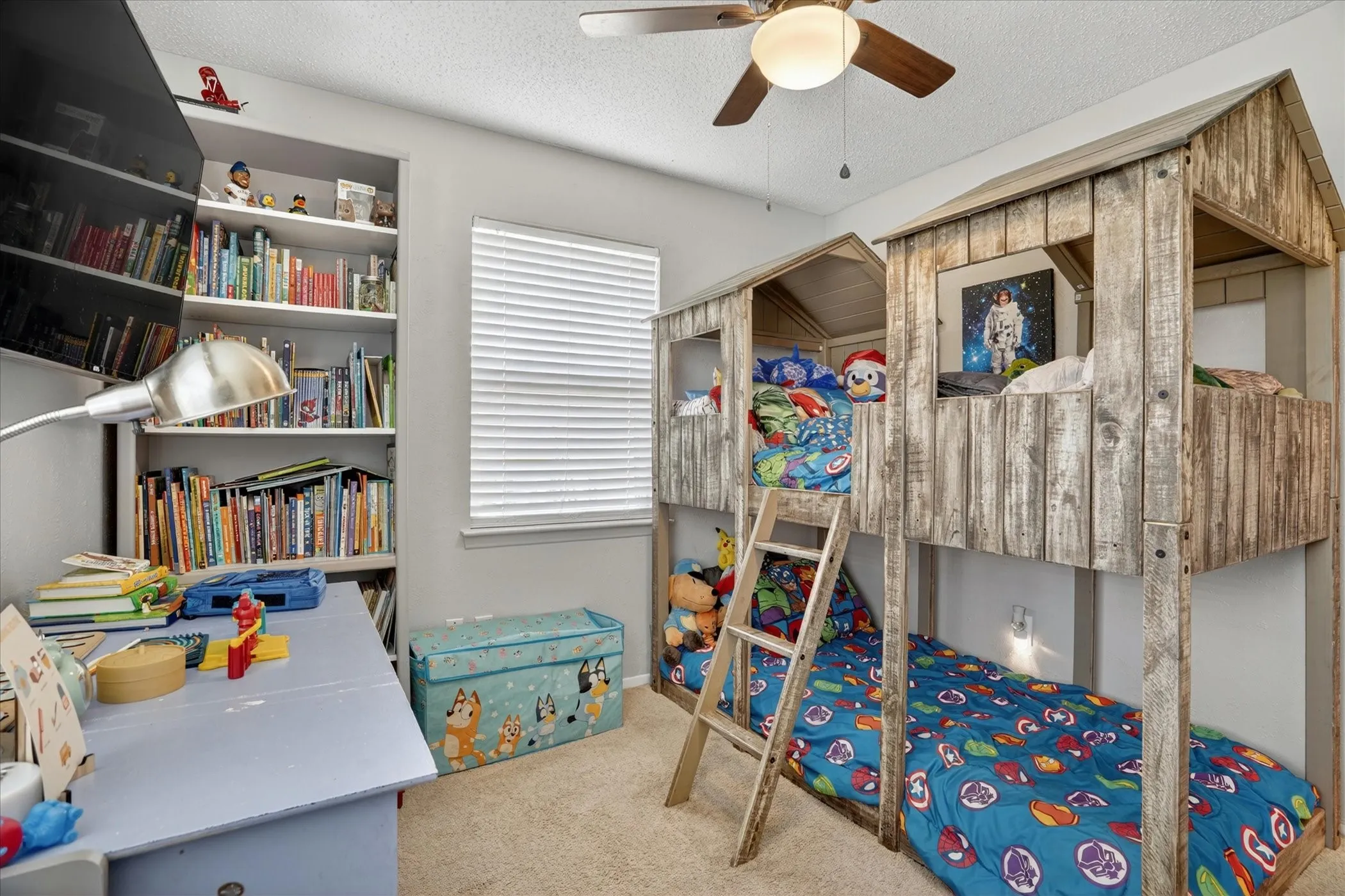 Built-in bunk beds with a rustic wood-finish facade, integrated shelving, an overhead ceiling fan with light, a window with blinds, and carpeted flooring