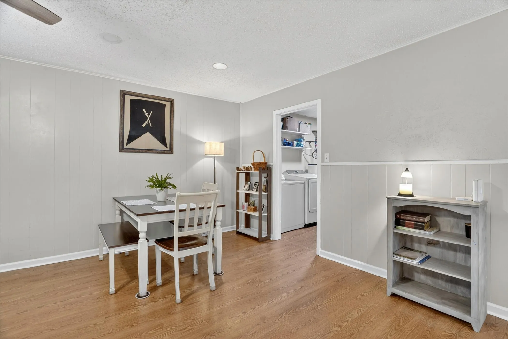 Light wood-finish flooring complements the paneling and white trim