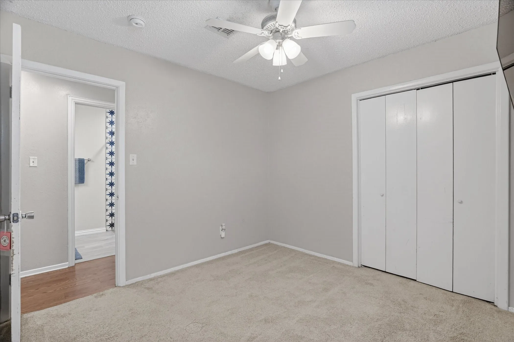 Neutral-toned room featuring carpet flooring, a ceiling fan with integrated lighting, and bi-fold closet doors
