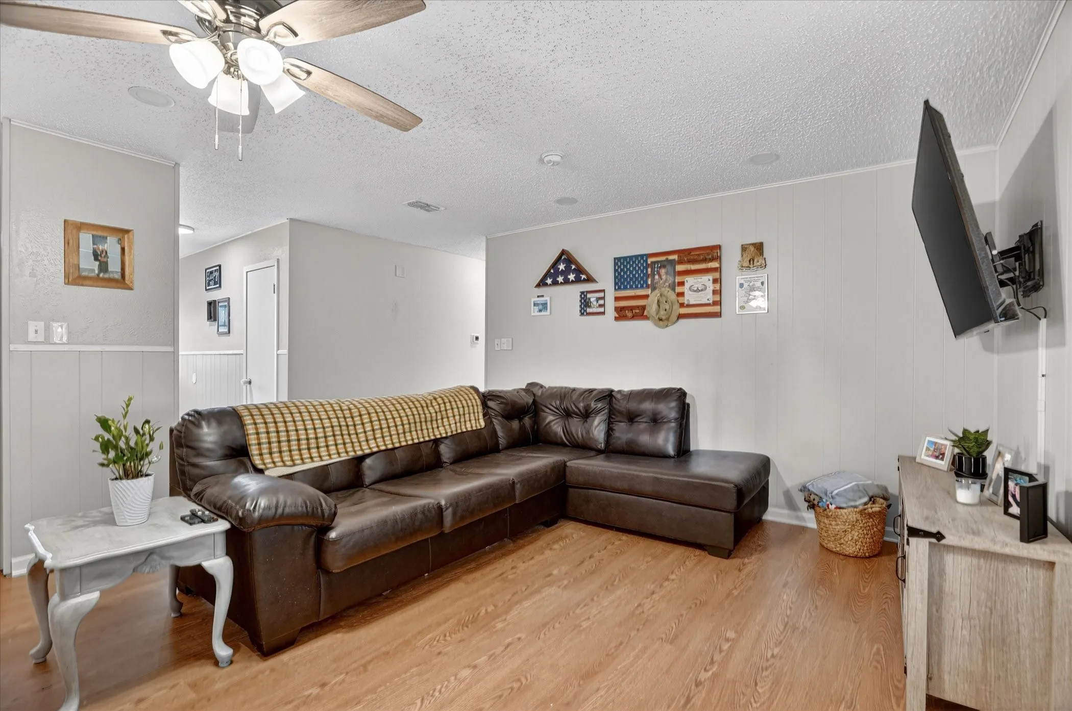 Open living area featuring wood-finish flooring, light gray walls, and white wainscoting