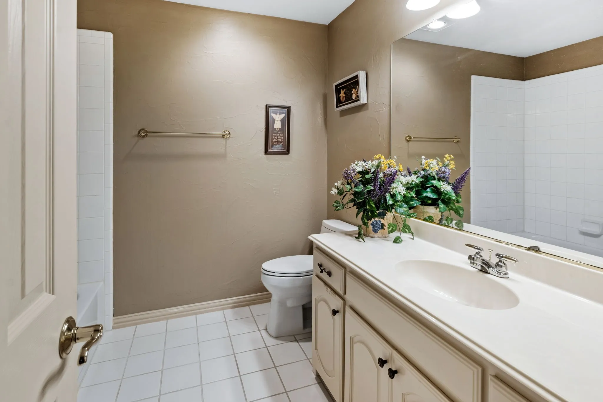 Bathroom featuring a white vanity with integrated sink, chrome faucet, and a large wall-mounted mirror
