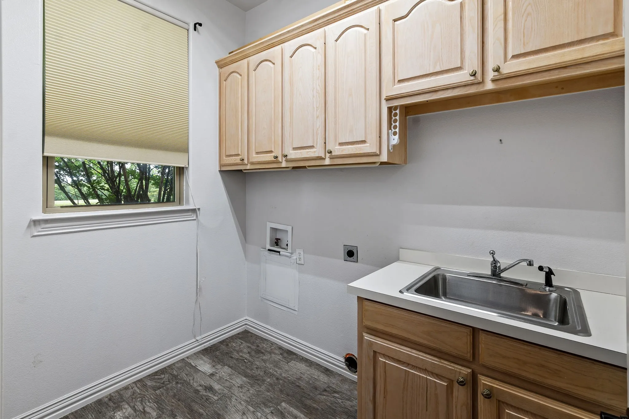 Utility space featuring wood-finish flooring, a window with cellular blinds, and a built-in sink with a countertop