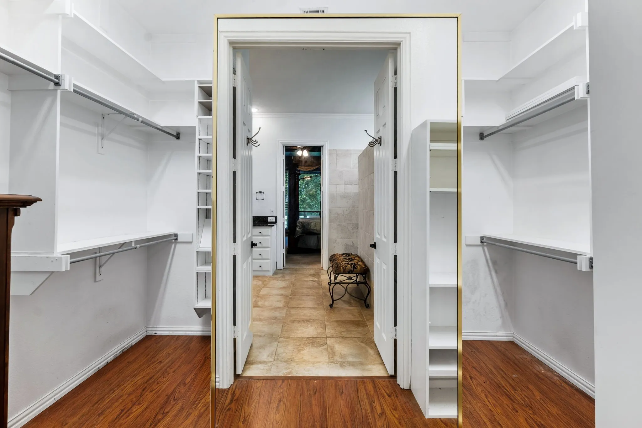 Walk-in closet featuring wood-finish flooring, white shelving, and hanging rods