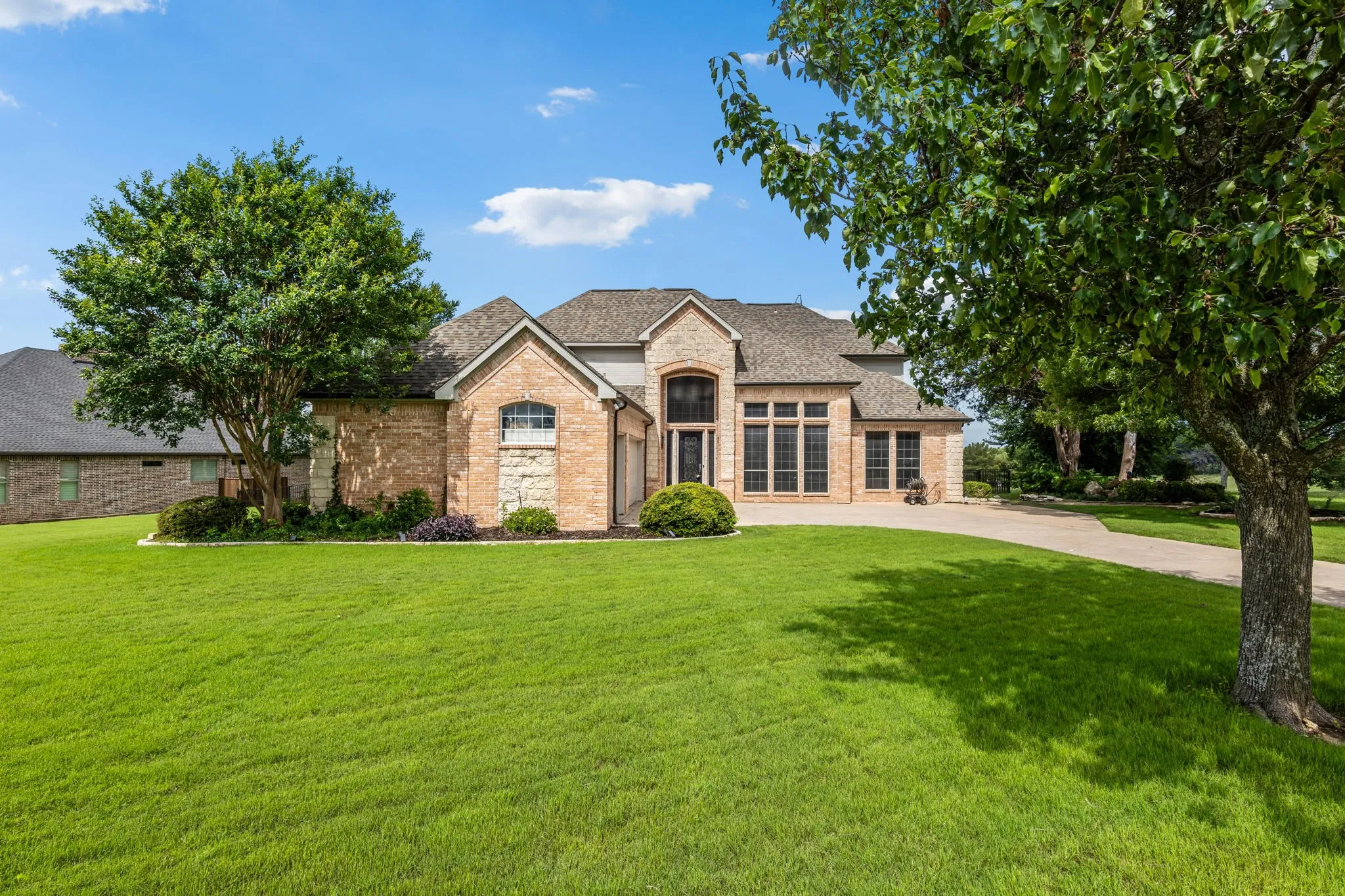 Brick and stone exterior featuring varied window designs, a prominent arched entrance, and a multi-level roofline