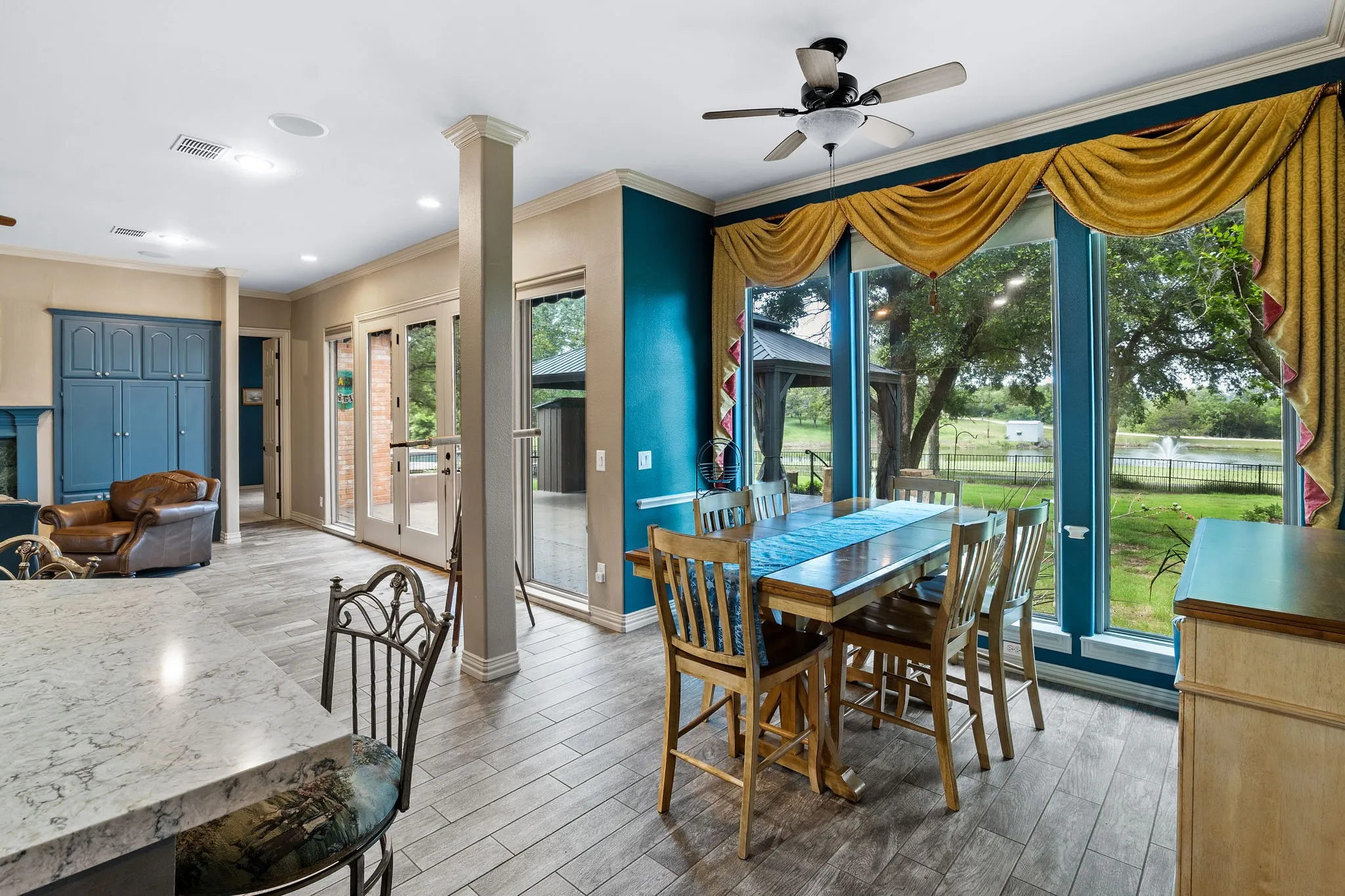 Open-concept living space featuring wood-finish tile flooring, a built-in cabinetry wall, and a column accent