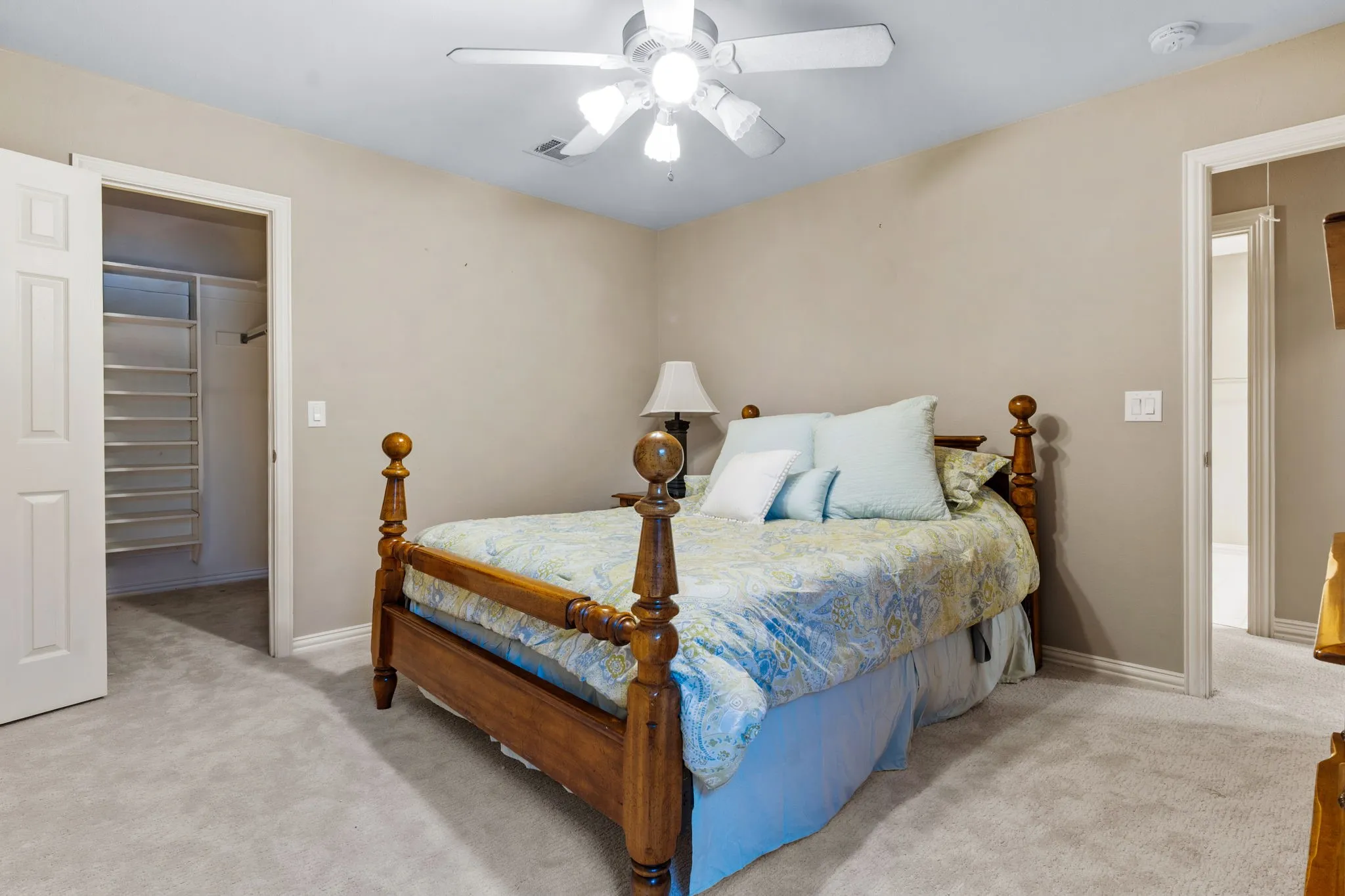 Carpeted room featuring a ceiling fan, baseboard molding, and a closet with built-in shelving