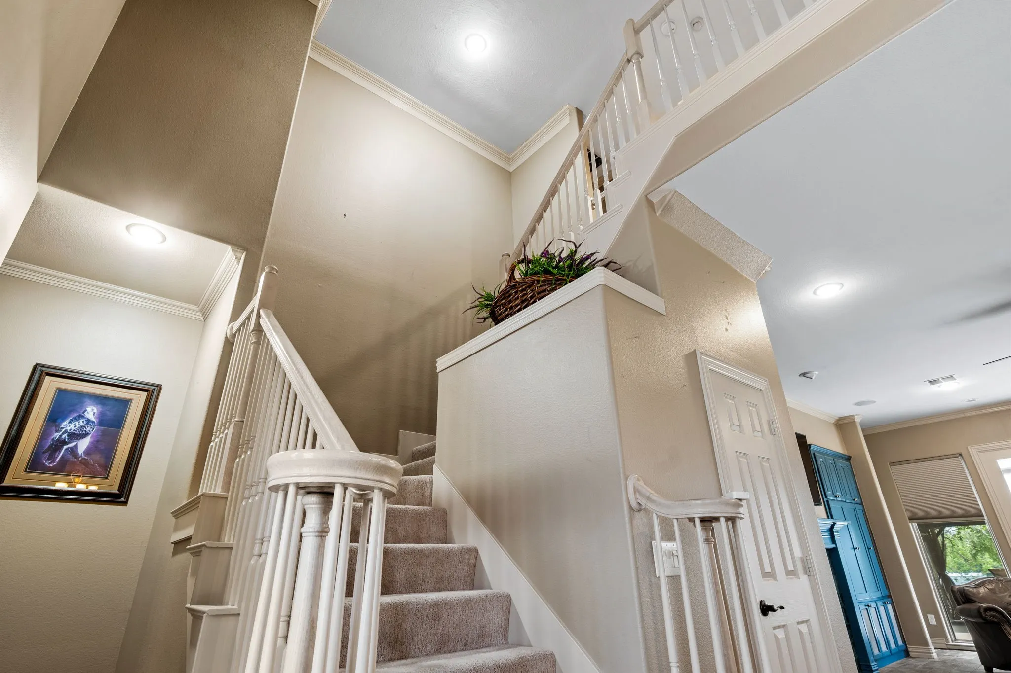 Staircase with carpeted treads and white painted balusters and newel posts