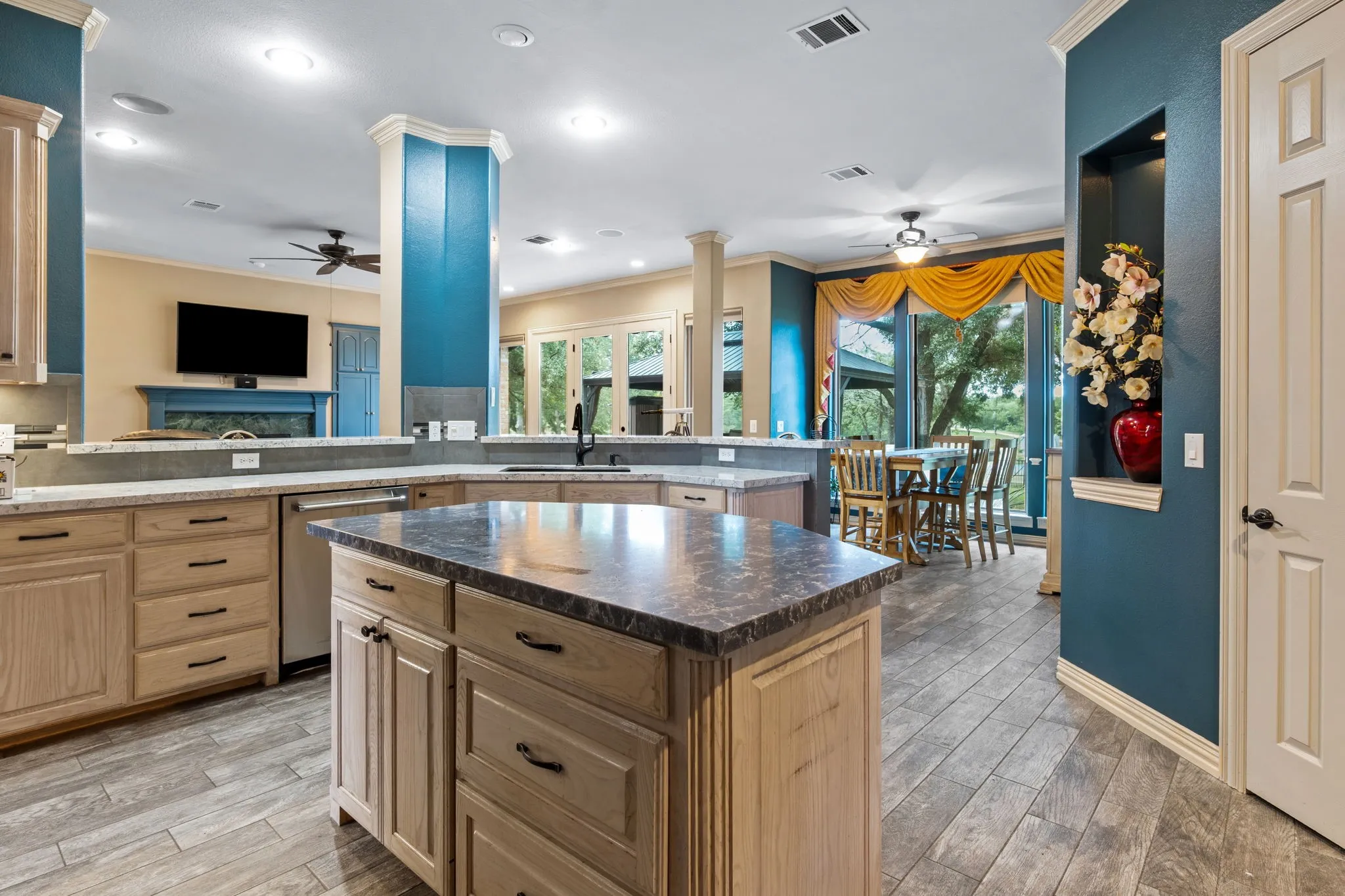 Open-concept kitchen featuring wood-finish flooring, light-toned cabinetry, a central island, and stone-look countertops