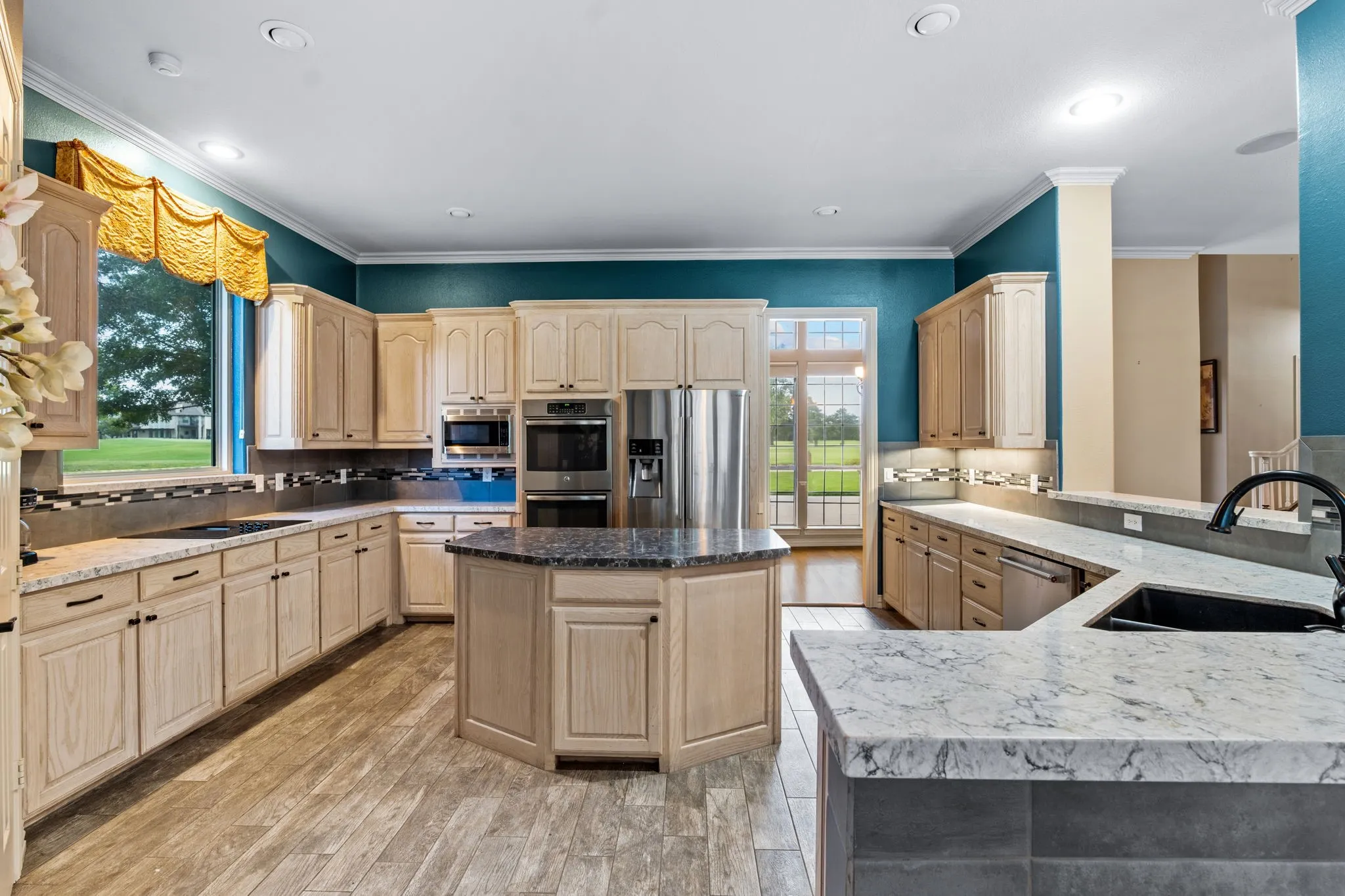 Spacious kitchen featuring light-toned cabinetry, stainless steel appliances, a center island with countertop, and wood-finish flooring