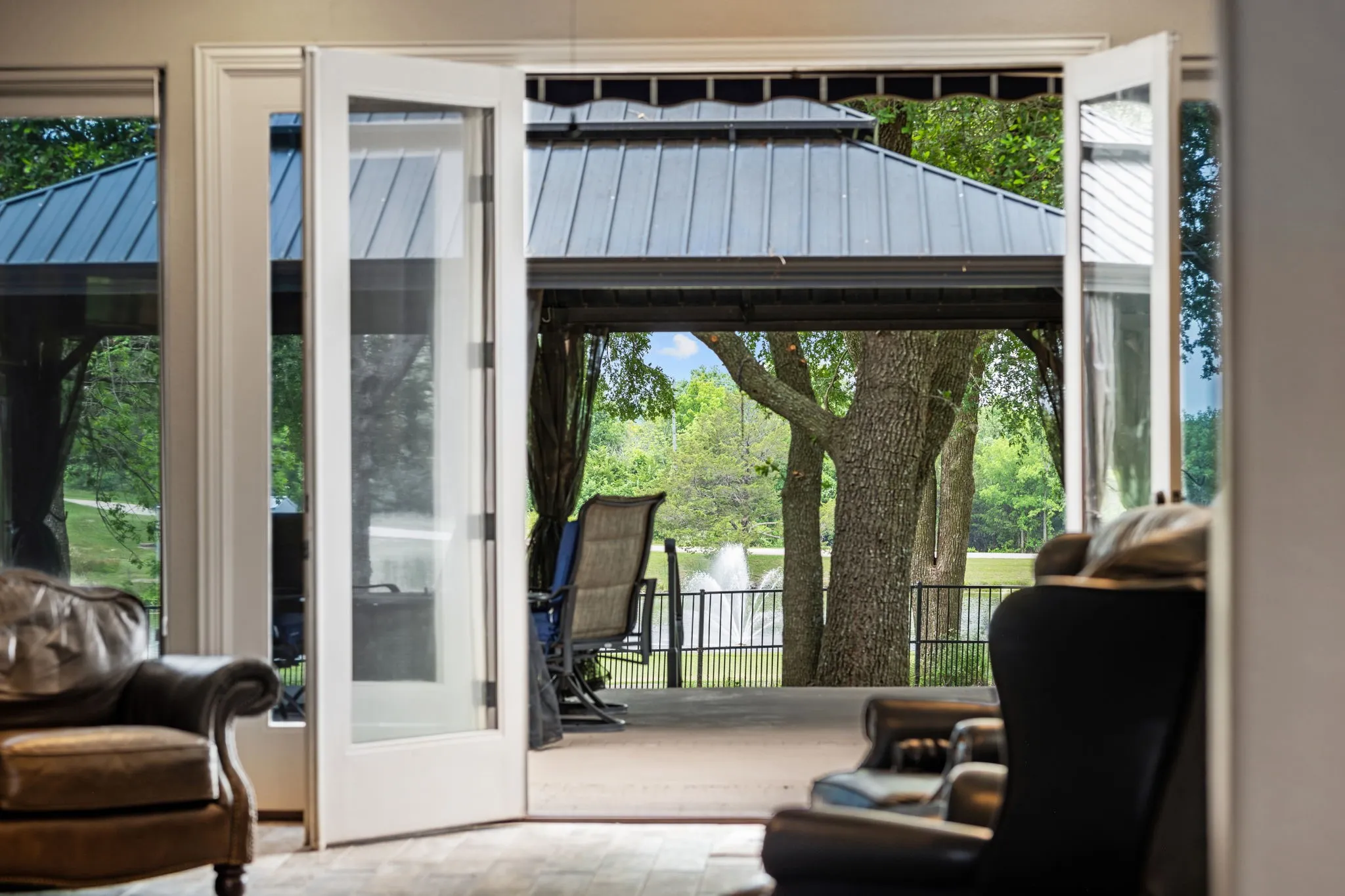 Glass-paneled French doors open to an outdoor patio featuring a covered gazebo with a dark metal roof