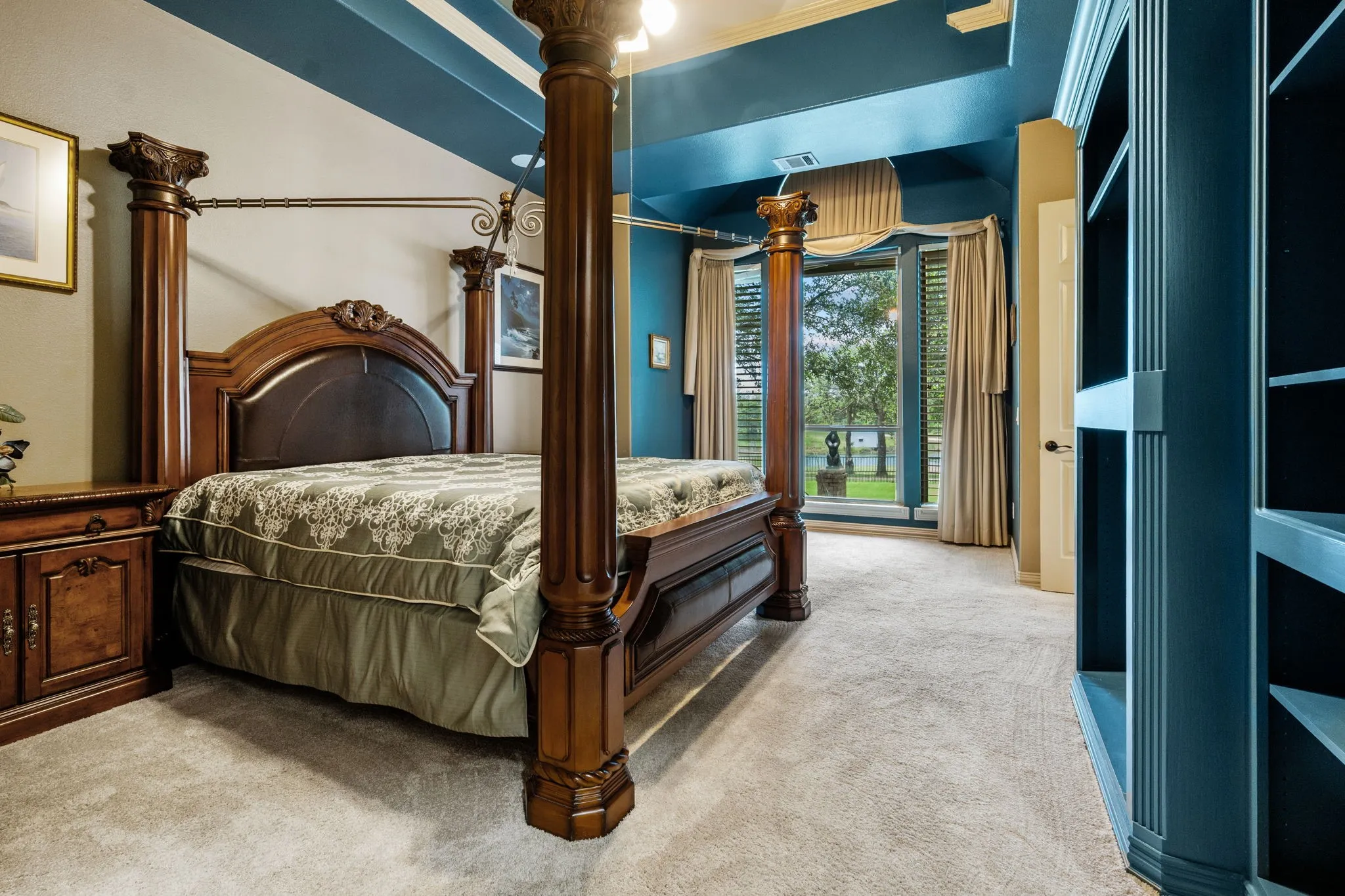 Carpeted interior space featuring a large window with outdoor scenery, built-in shelving, decorative wall paneling, and a distinct ceiling design