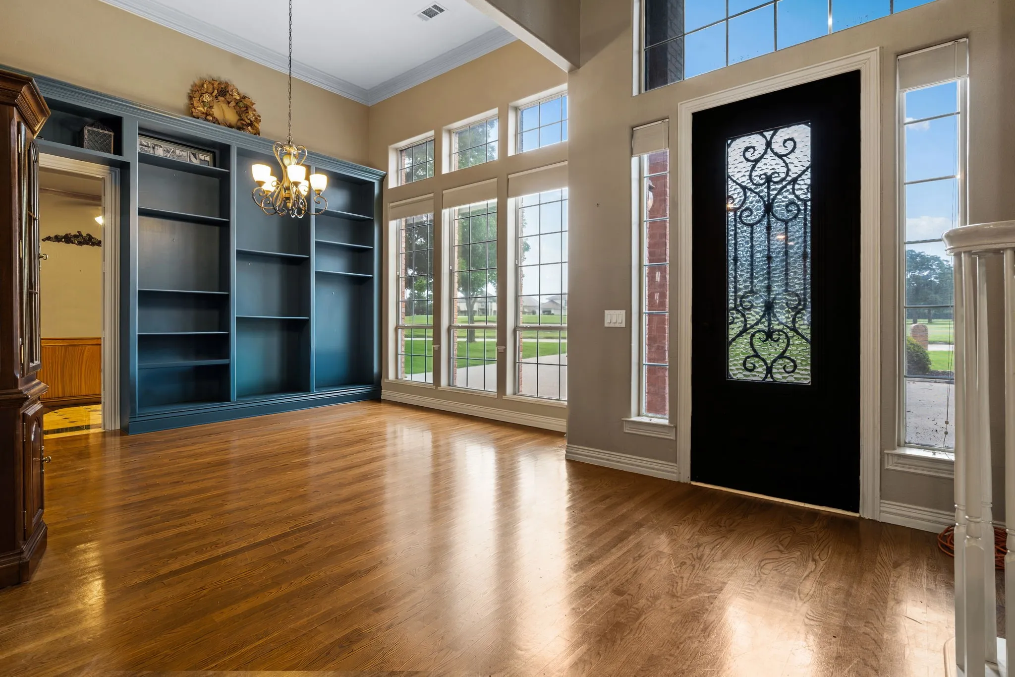 Grand entry featuring a dark wood door with decorative wrought iron and frosted glass insert, flanked by tall sidelight windows