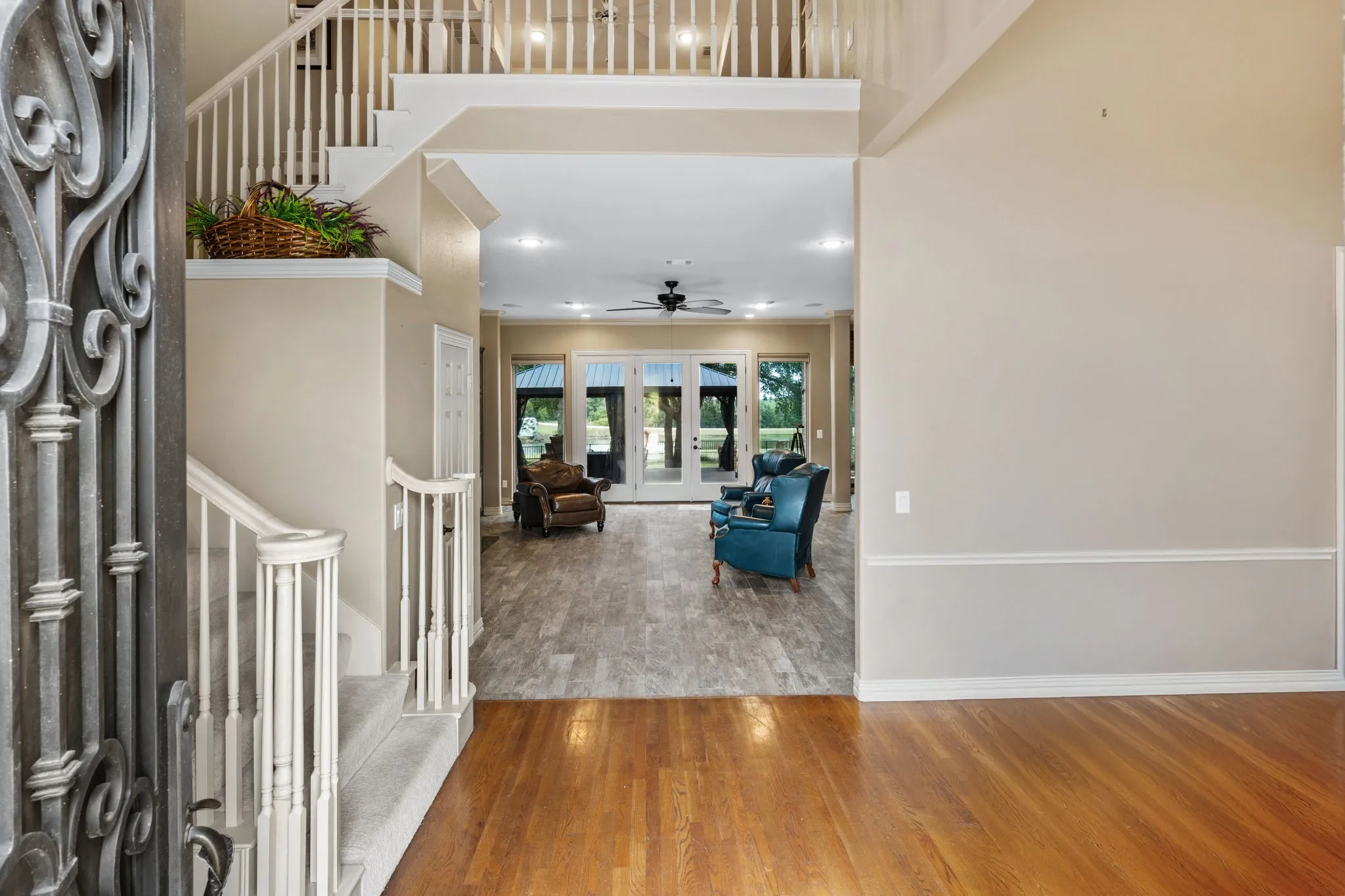 Two-story foyer featuring a grand staircase with white balusters, wood-finish flooring, and an ornate wrought-iron entry door
