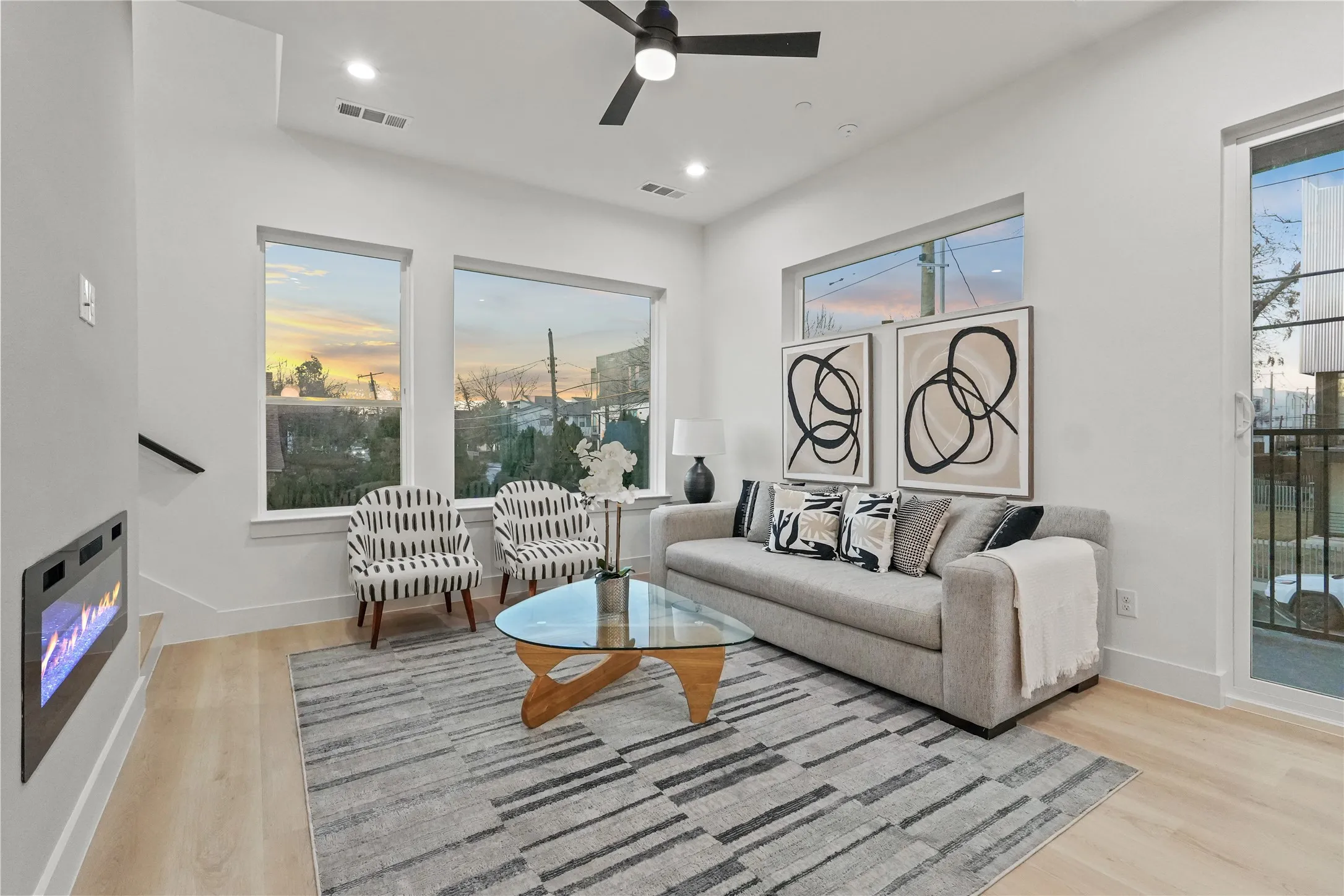 Living area with a glass covered fireplace, ceiling fan, light wood finished floors, and recessed lighting