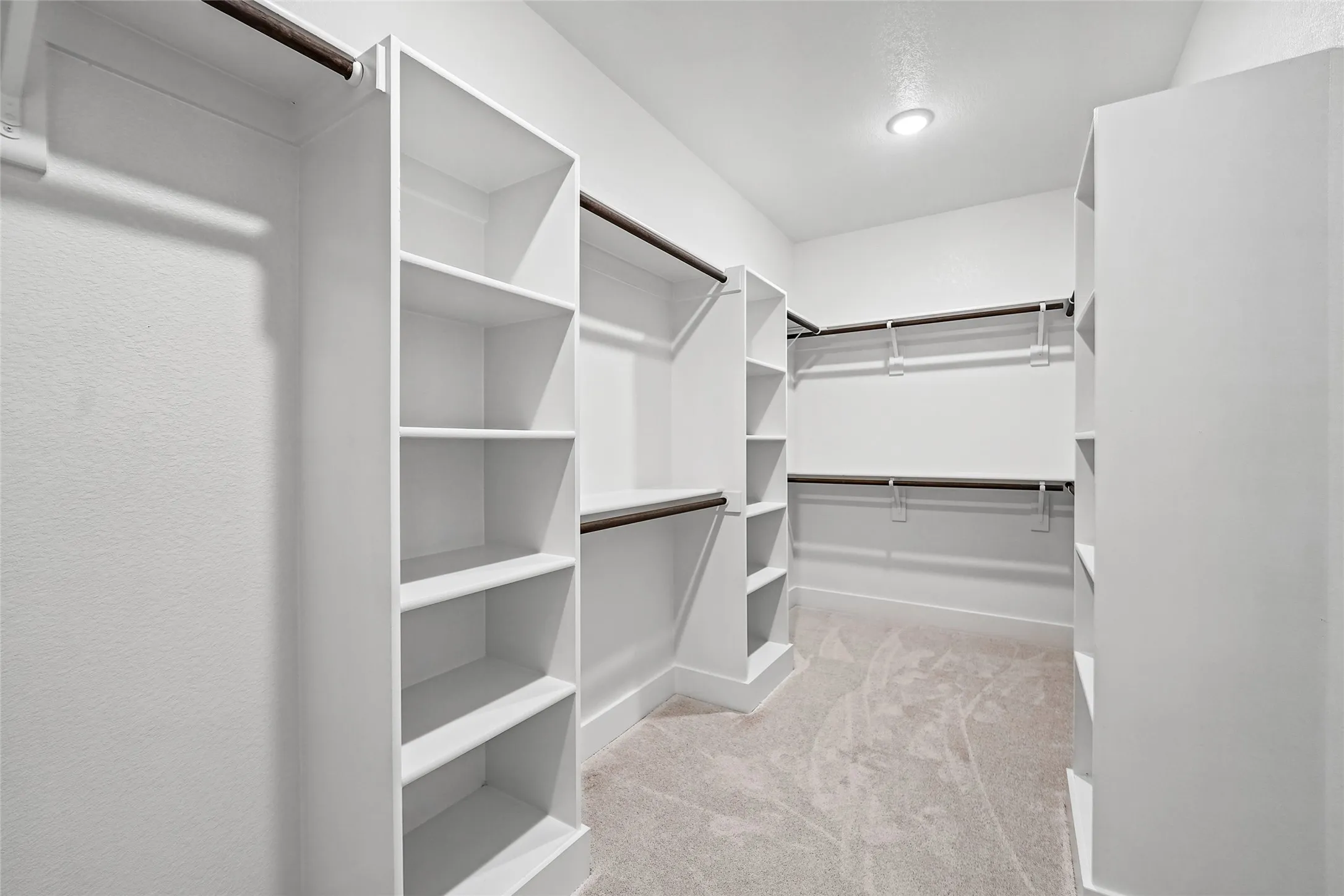 Walk-in closet with built-in shelving, multiple hanging rods, recessed lighting, and carpet flooring