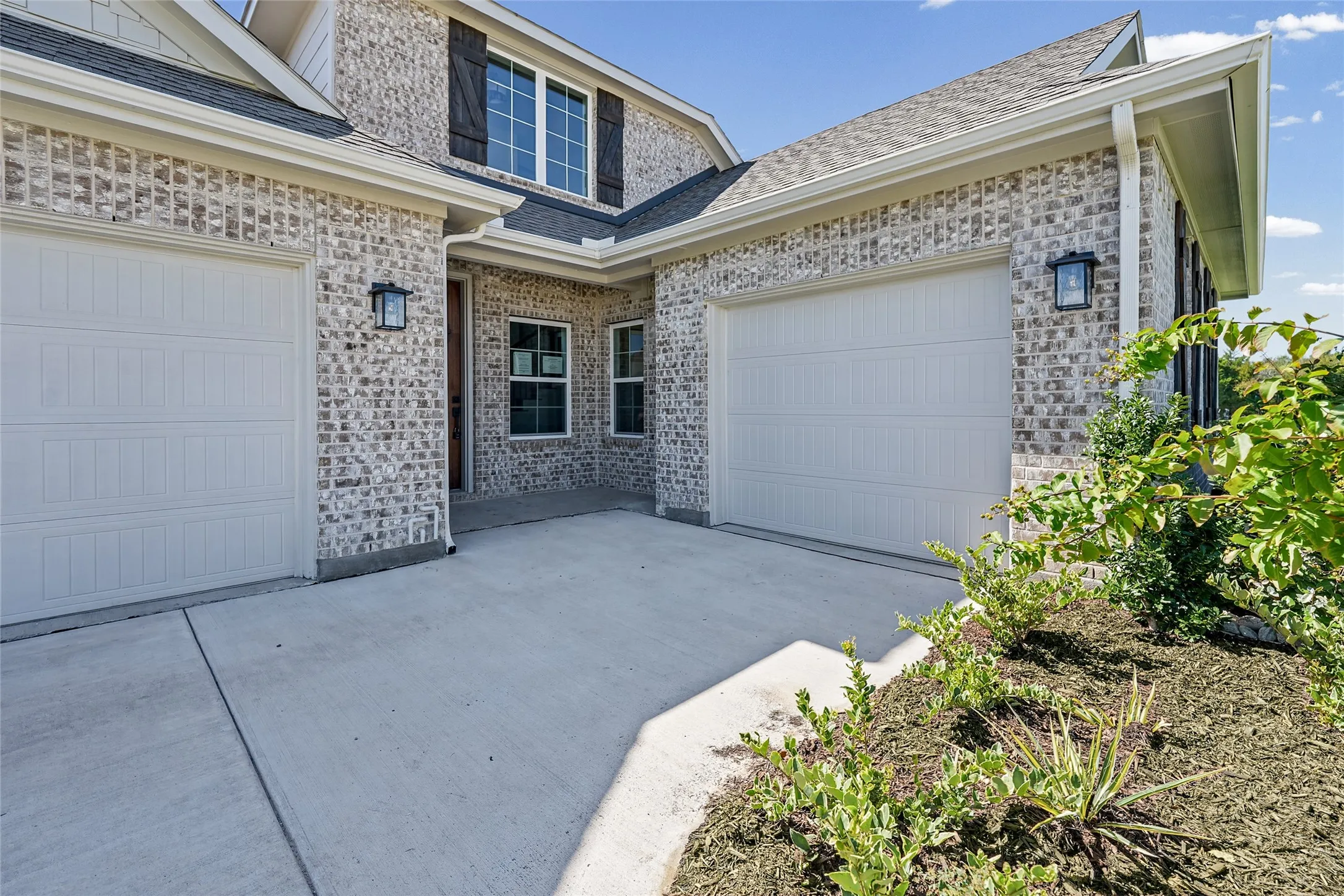 Brick exterior with gray-toned variegated masonry and white garage doors