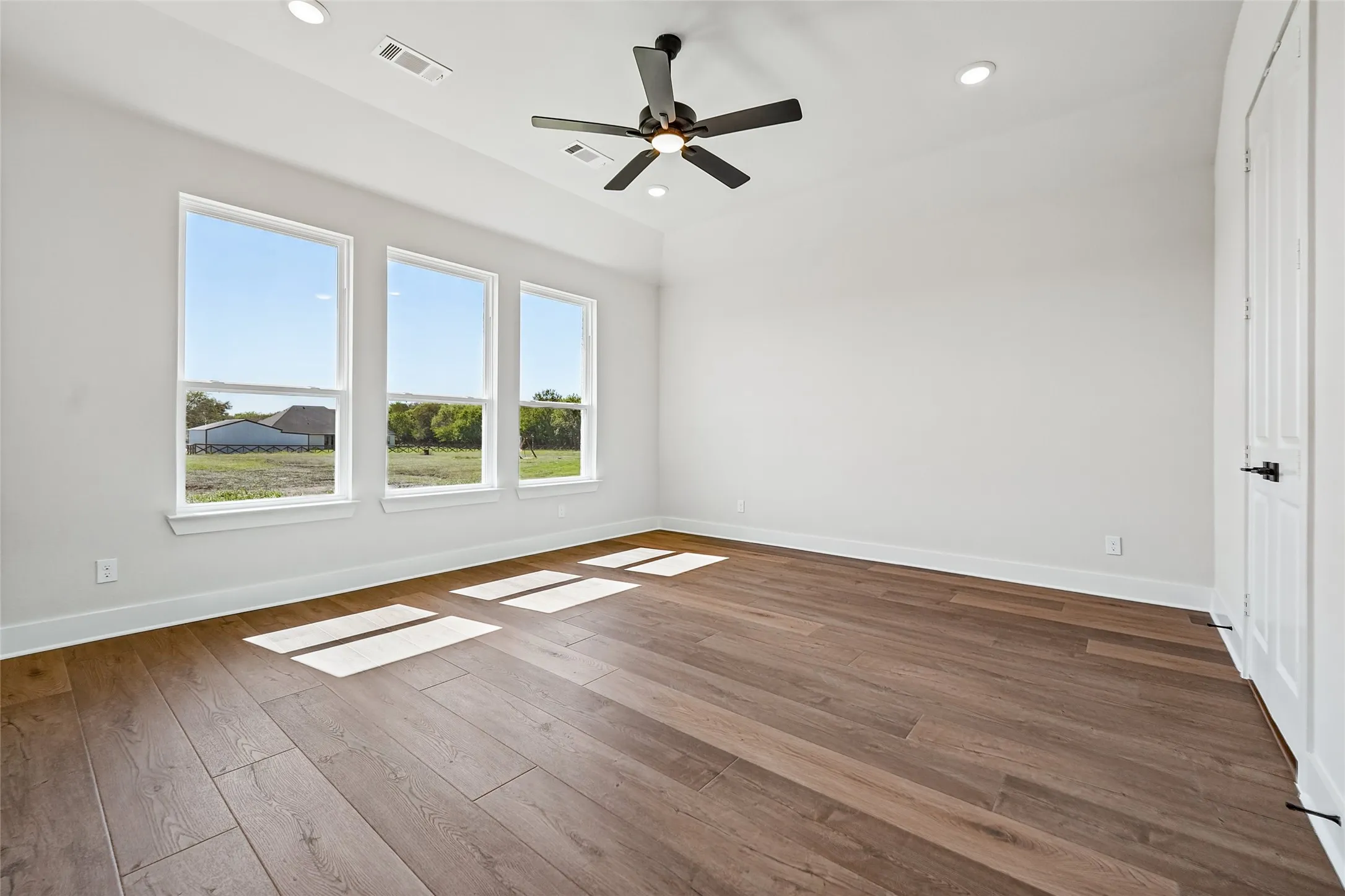 Vaulted ceiling, recessed lighting, wood-finish flooring, ceiling fan, and multiple windows