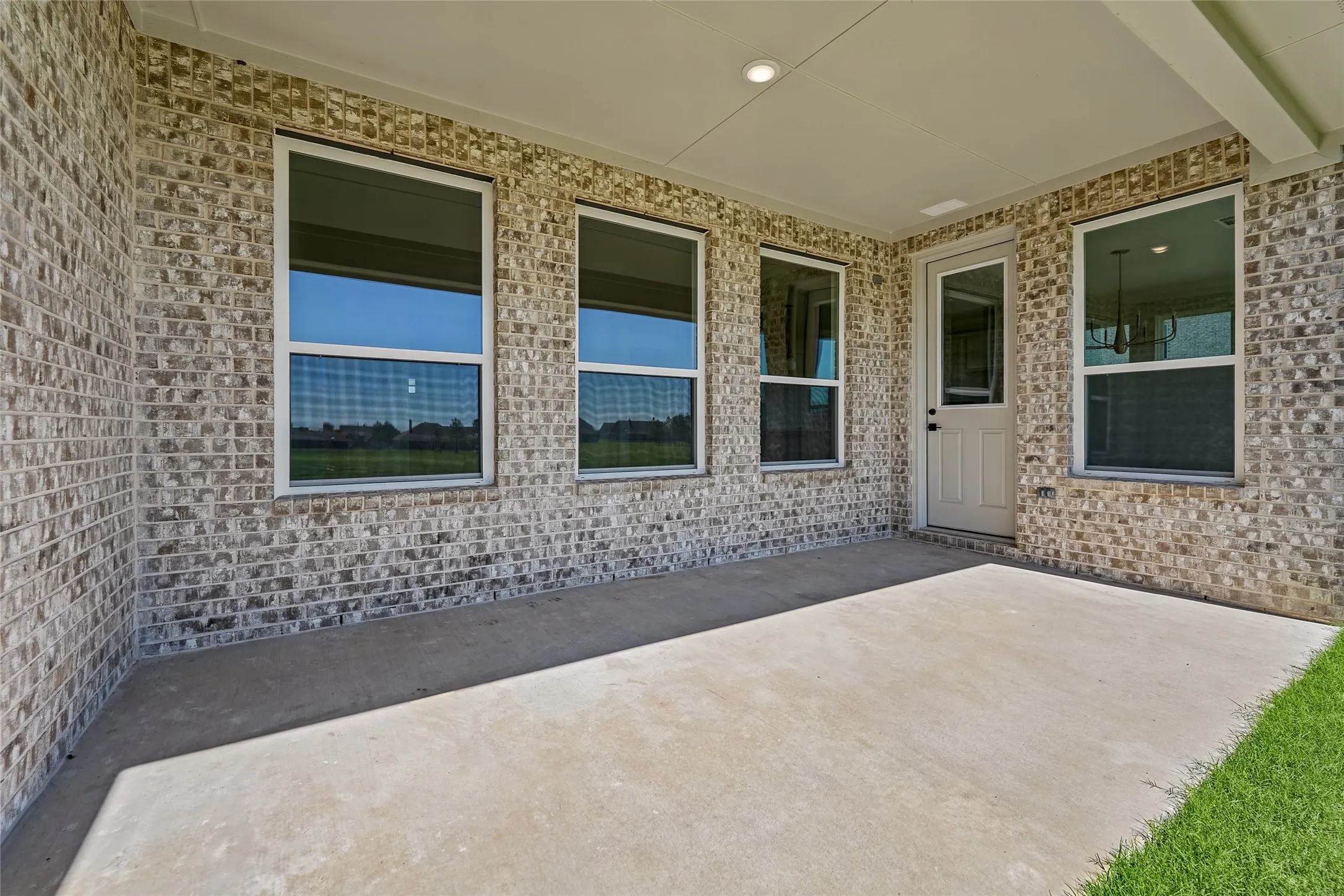 Covered patio featuring a concrete slab, brick exterior, and a glass-paneled door
