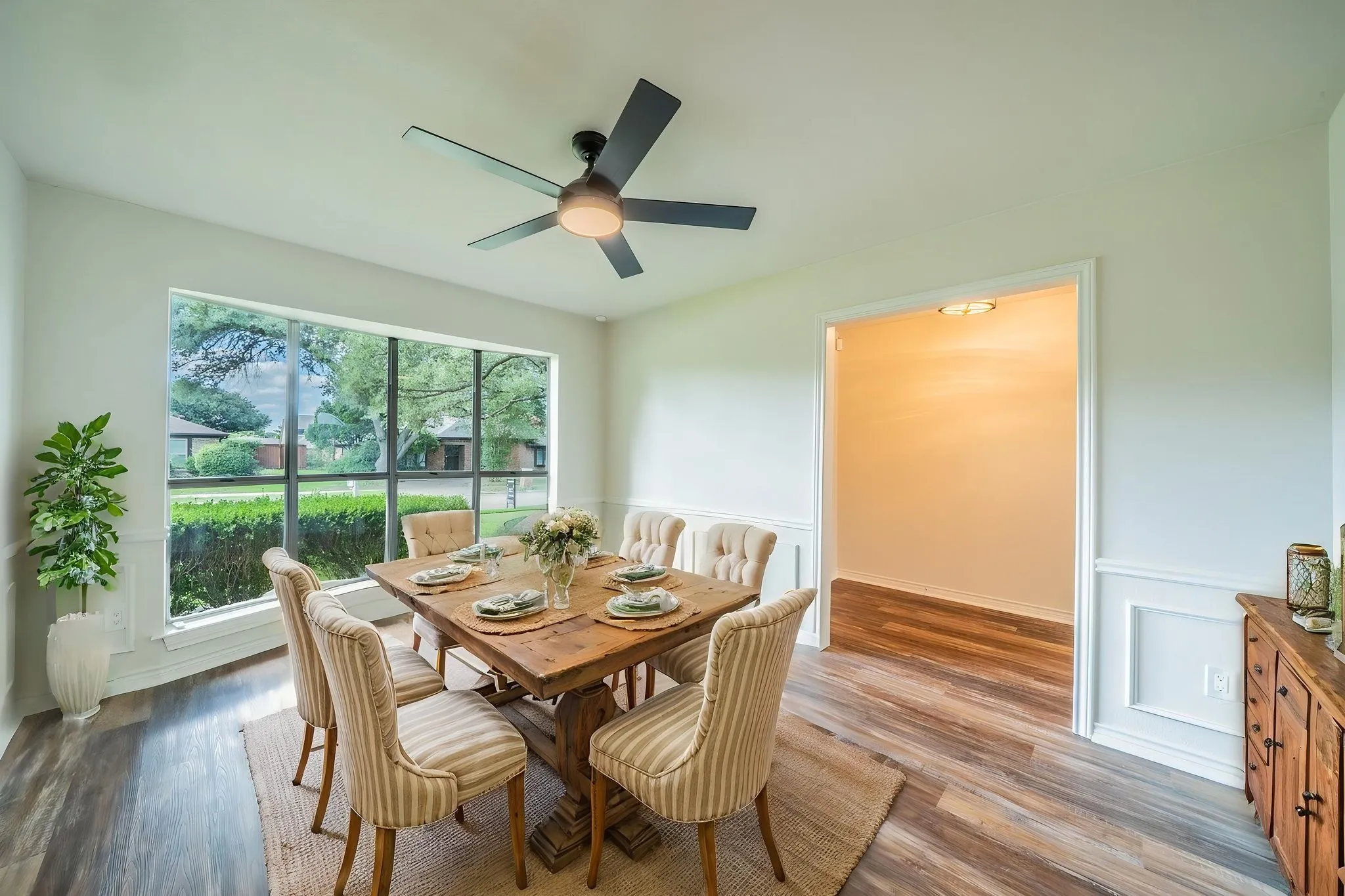 Virtually Staged. Spacious room featuring a large picture window, wood-finish flooring, and crown molding