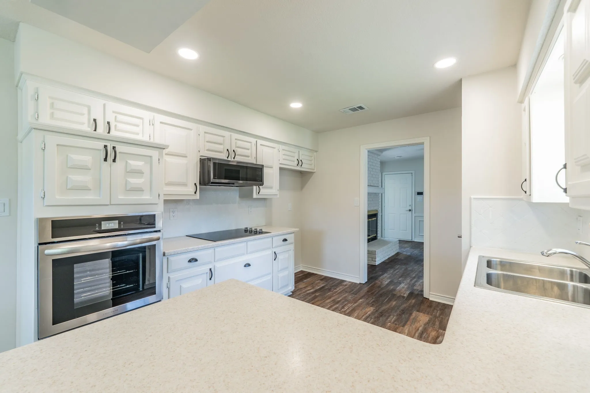 Kitchen featuring white cabinetry, built-in stainless steel oven, electric cooktop, and dual basin sink
