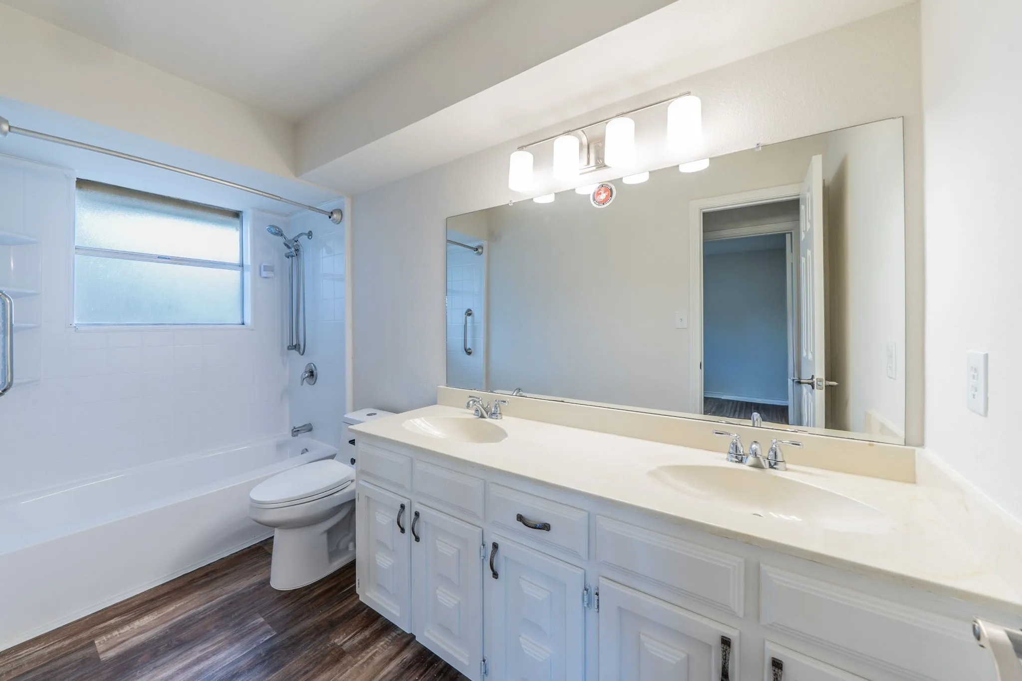 Double vanity with integrated sinks, white cabinetry, and wood-finish flooring