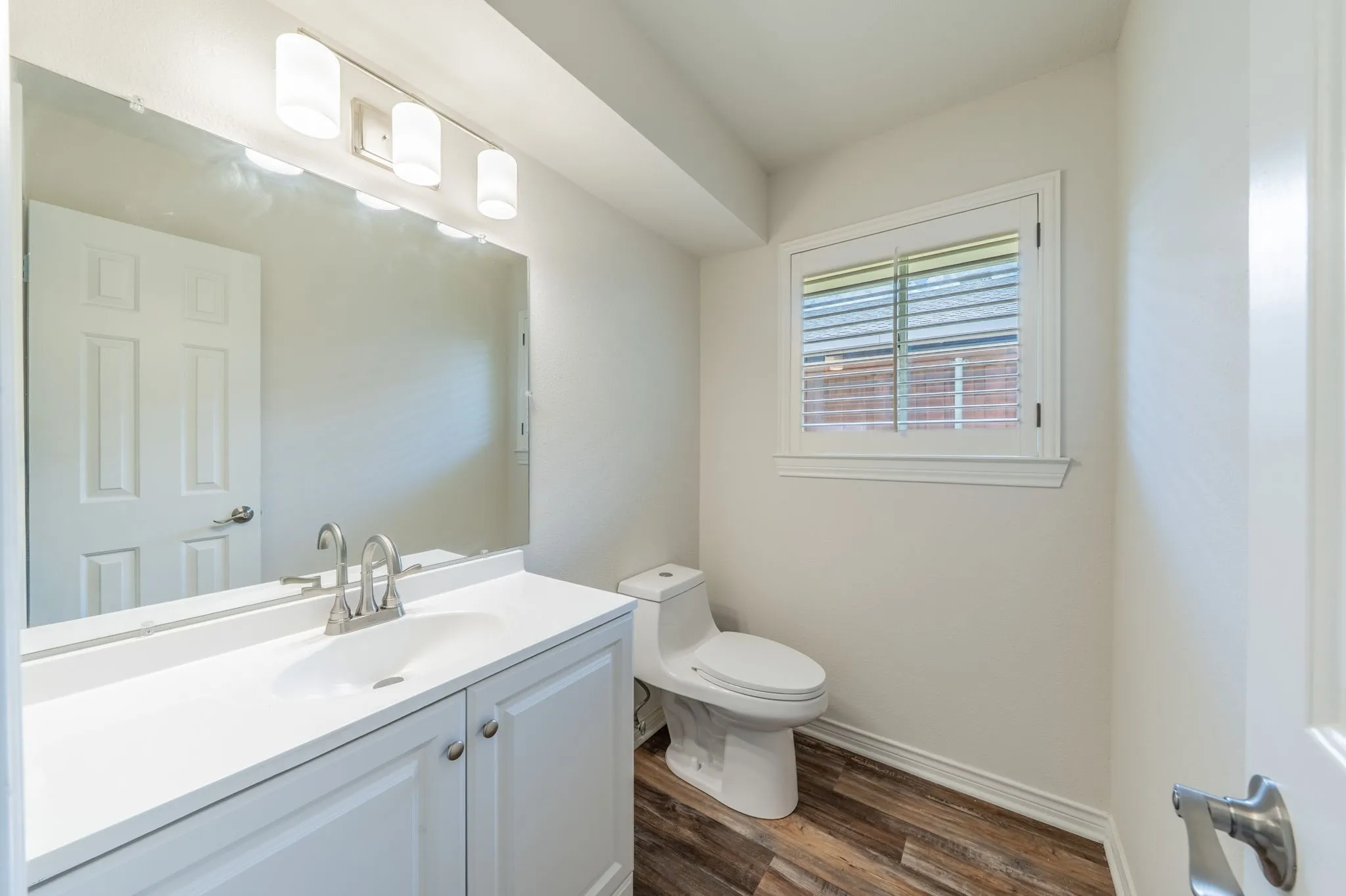 Half Bathroom with a white vanity featuring a single sink, brushed nickel faucet, and white cabinetry