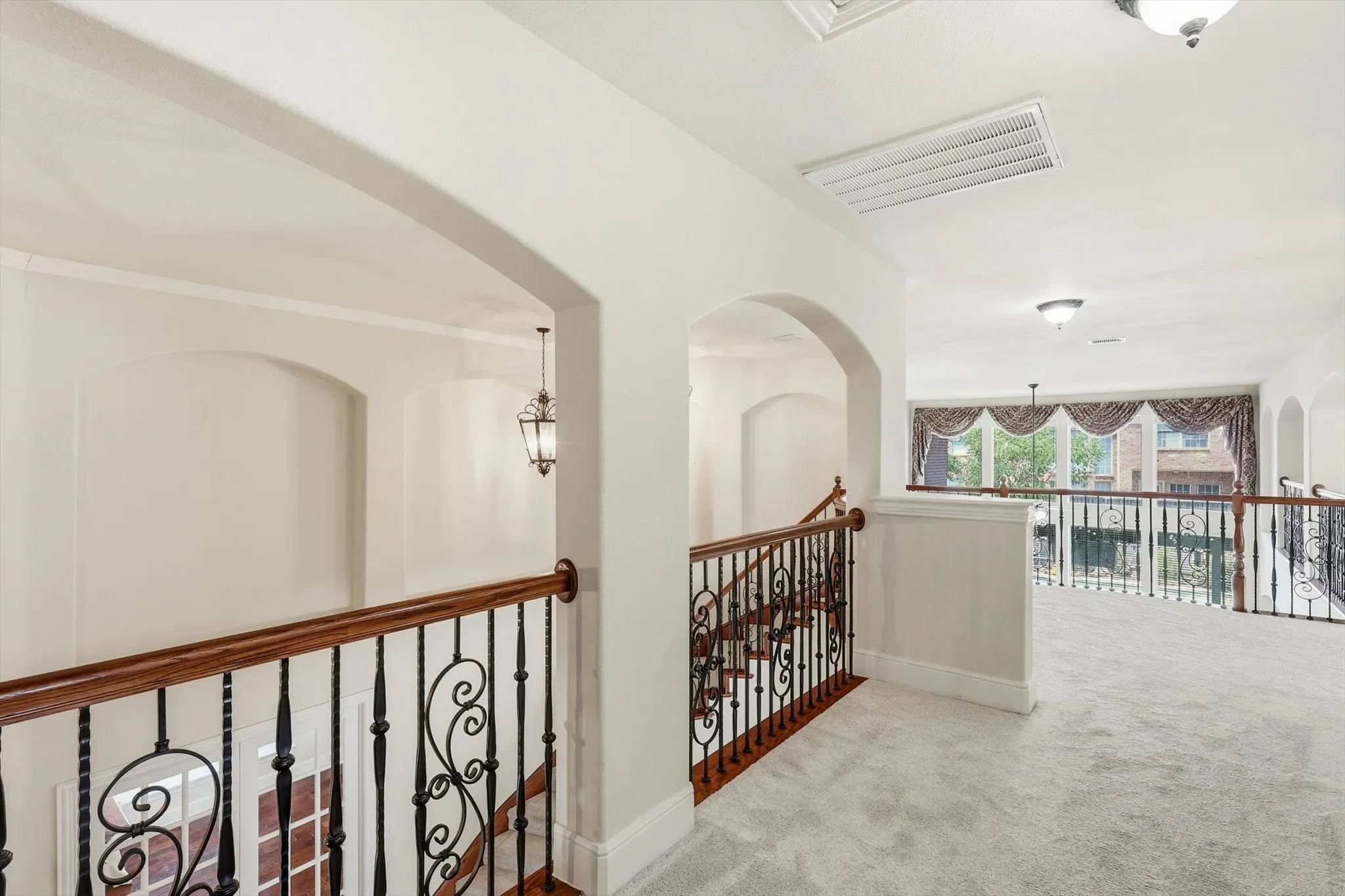 Arched architectural details, wrought iron and wood stair railing, recessed wall niches, and light-colored carpeting