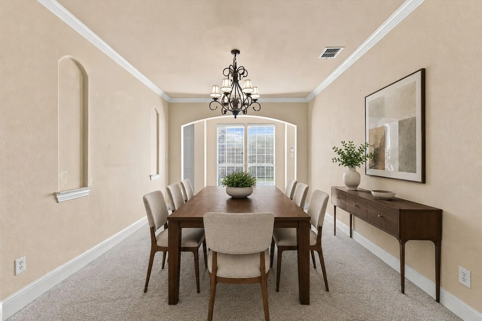 Virtually Staged Recessed wall niches, crown molding, arched entryways, and a wrought iron chandelier