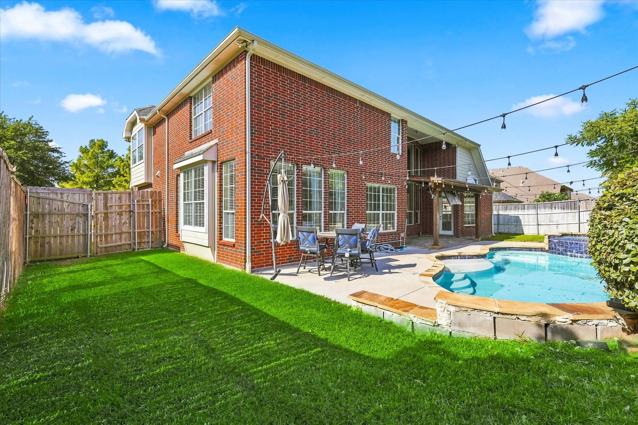 Brick exterior with bay windows, a private pool, and a paved patio area