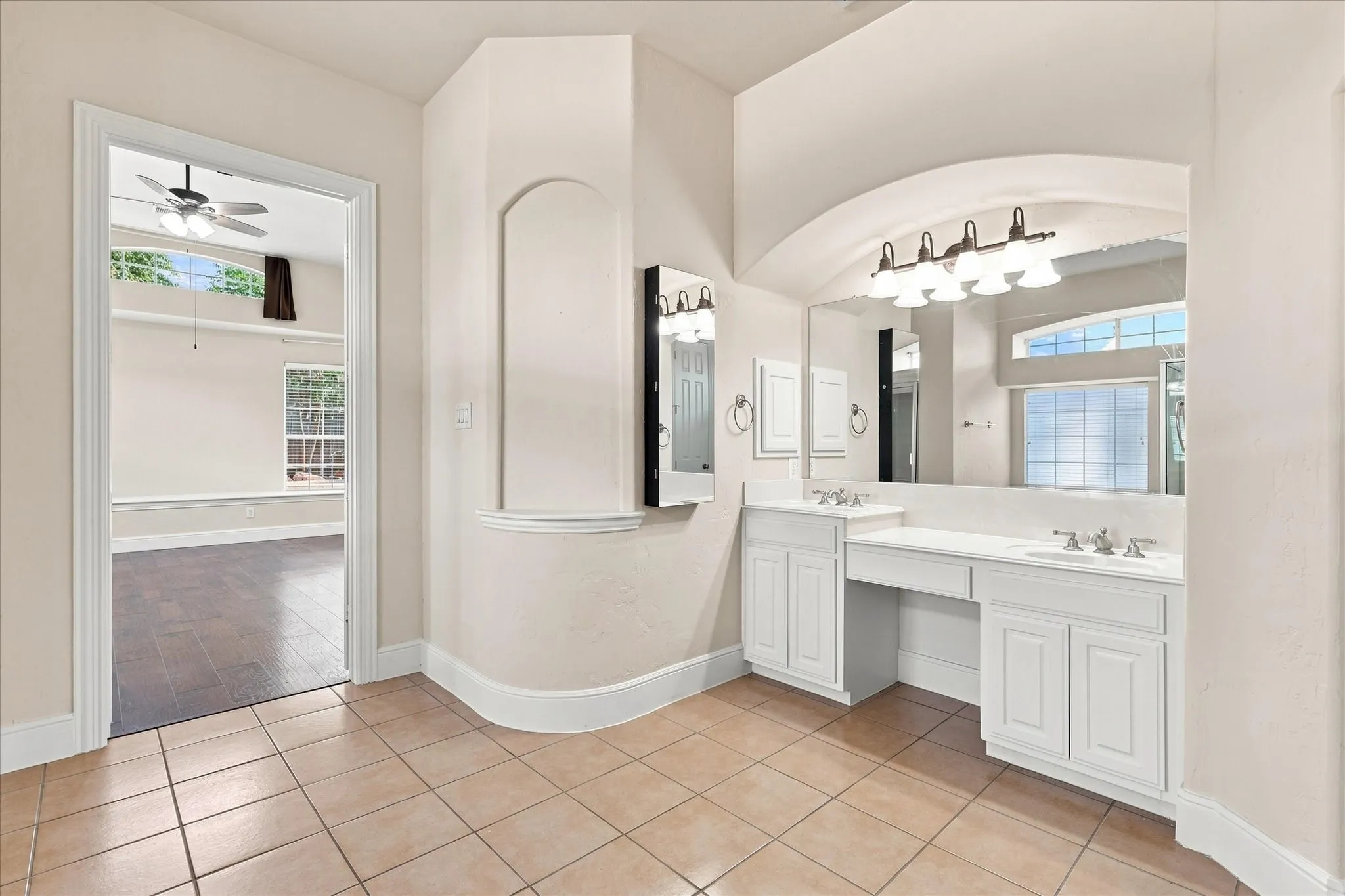 Dual vanity with integrated sinks, white cabinetry, and a large wall-mounted mirror