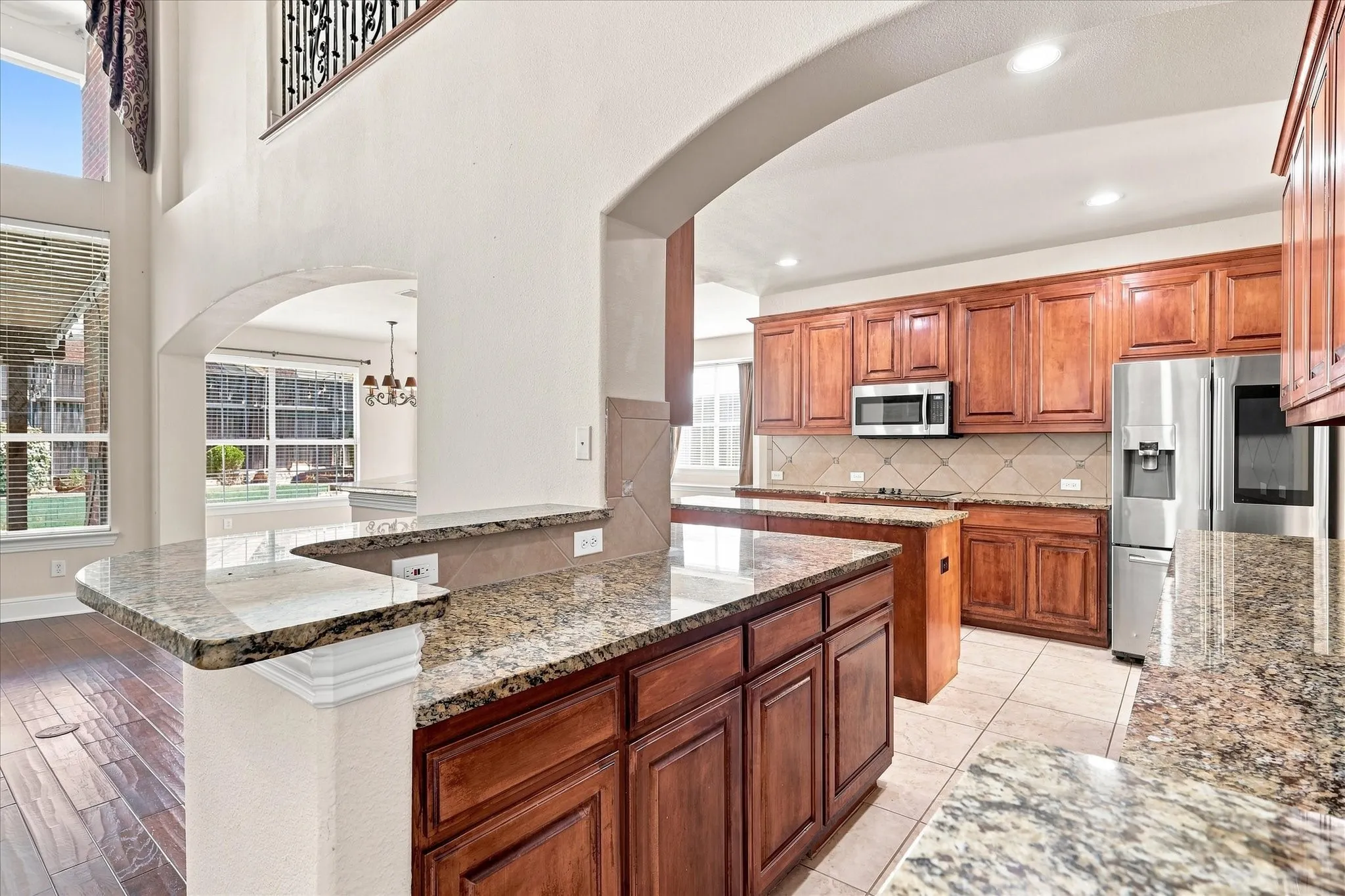 Kitchen featuring wood-finish cabinetry, stainless steel appliances, granite countertops, and tile flooring