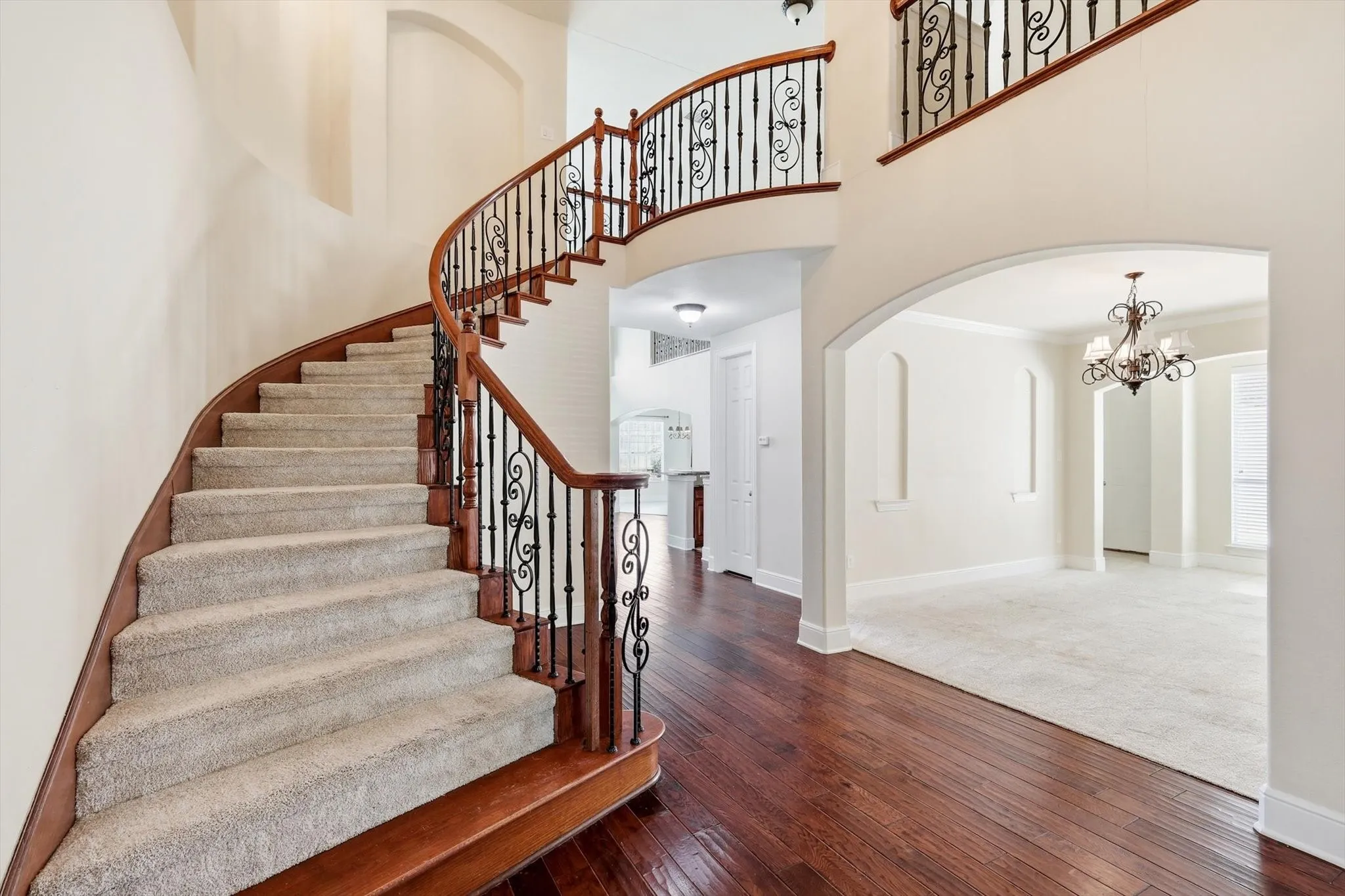 Grand curved staircase with decorative wrought iron balusters and rich wood handrails