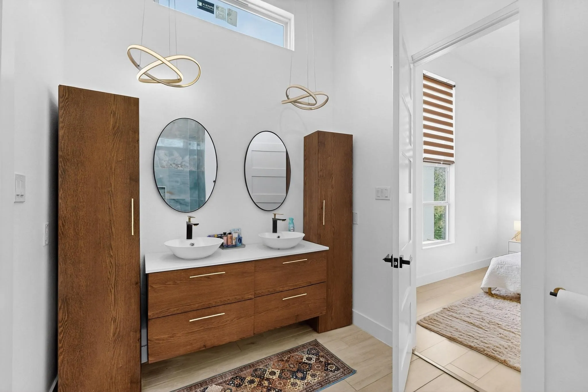 Modern vanity featuring dual vessel sinks, wall-mounted faucets, and two oval framed mirrors