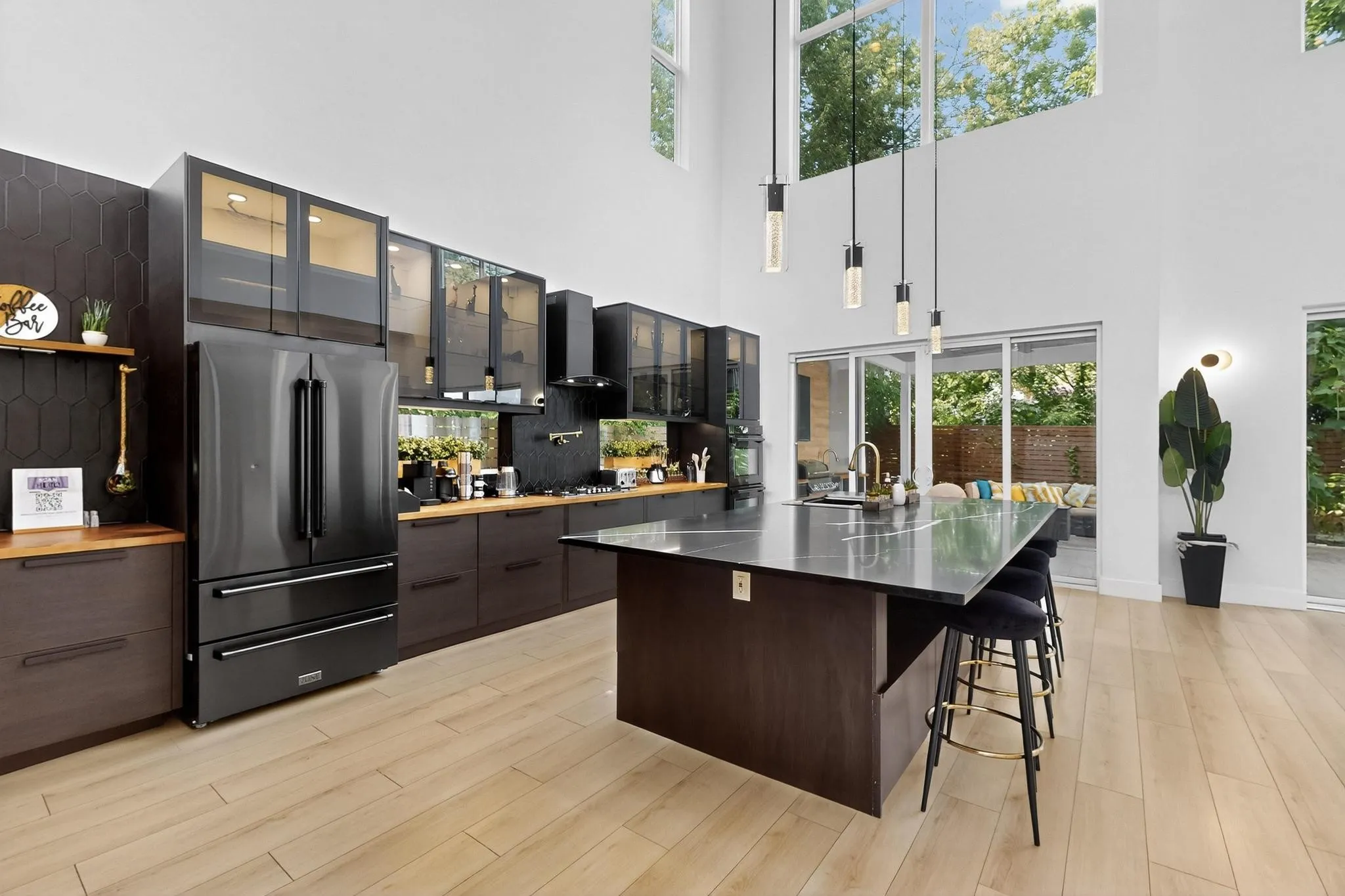 Modern kitchen featuring light wood-finish flooring, dark cabinetry, and a large central island with a dark countertop