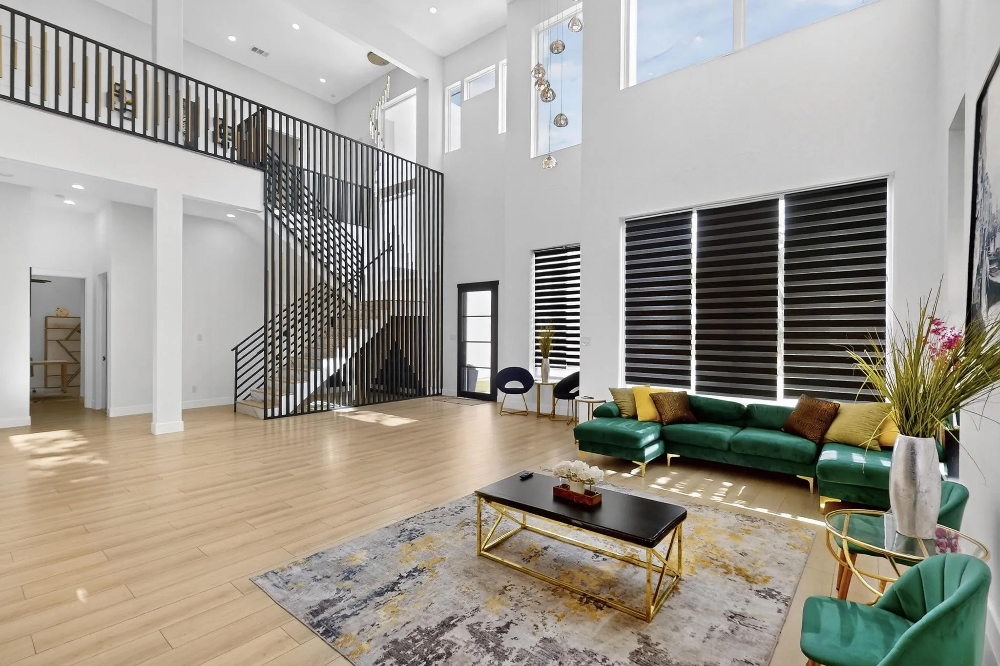 Expansive living area with high ceilings, wood-finish flooring, and a contemporary open staircase