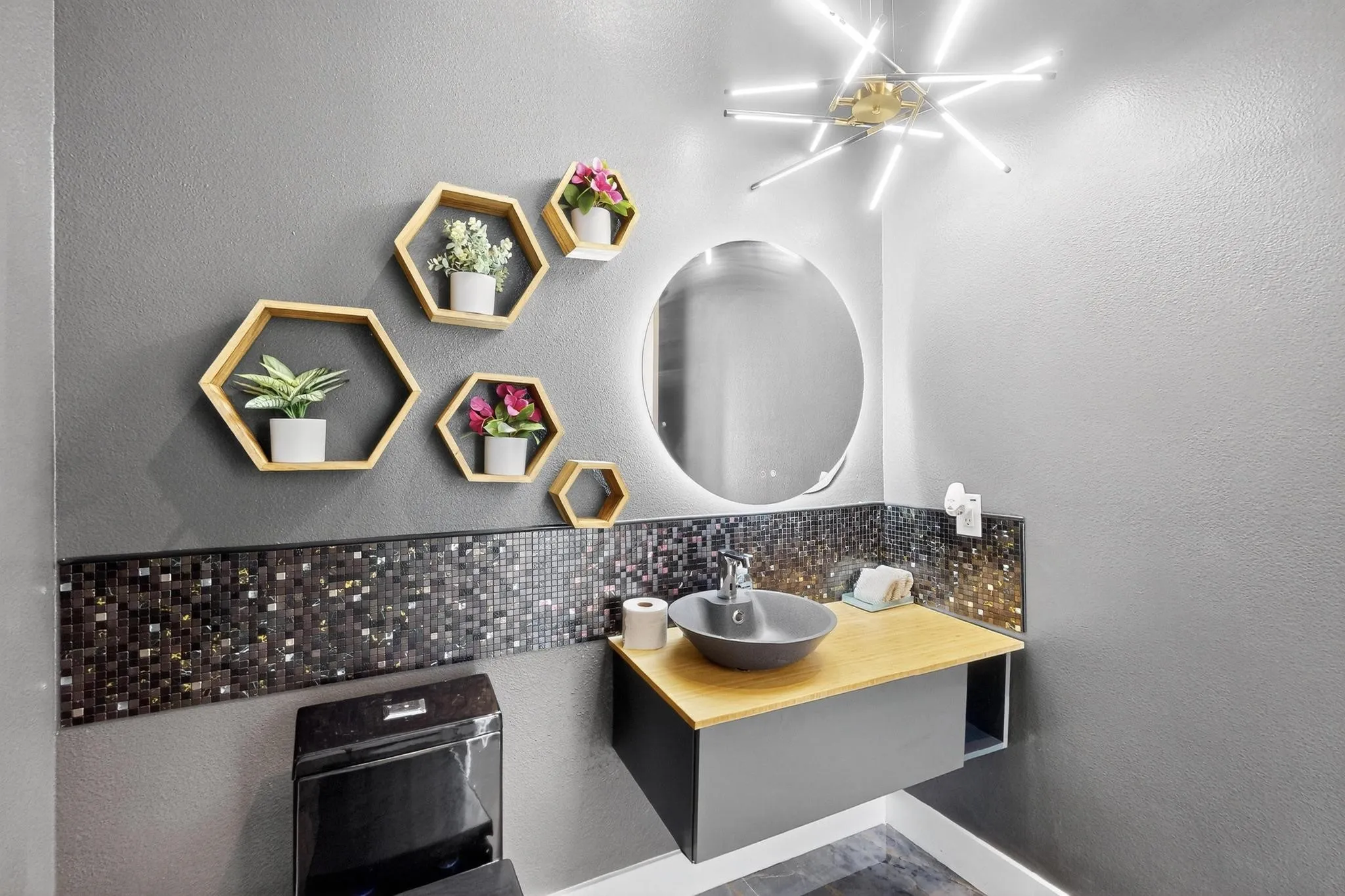 Modern vanity featuring a vessel sink, wood-finish countertop, and black mosaic tile backsplash