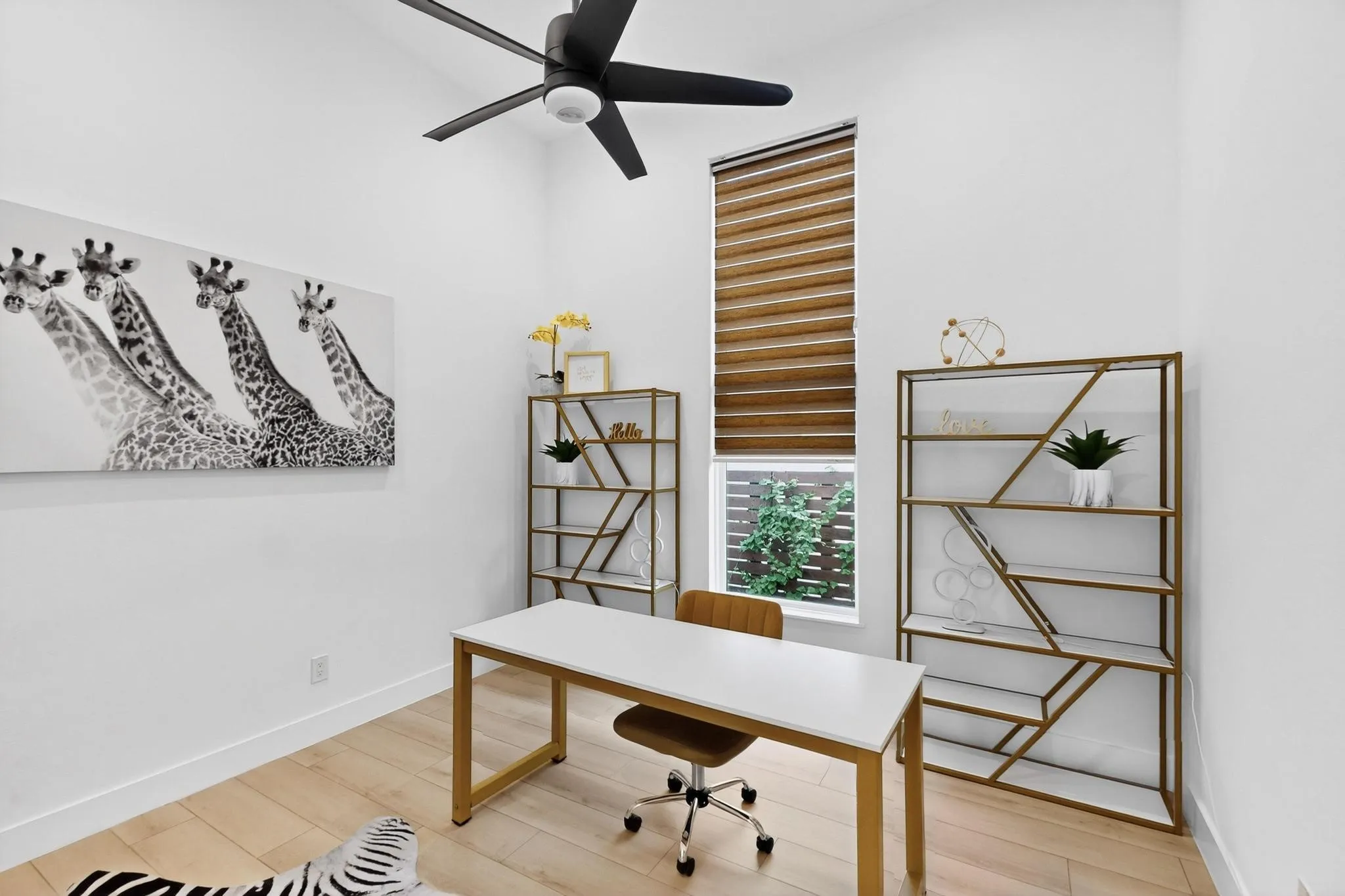 Vaulted ceiling with a black ceiling fan, wood-finish flooring, and crisp white walls